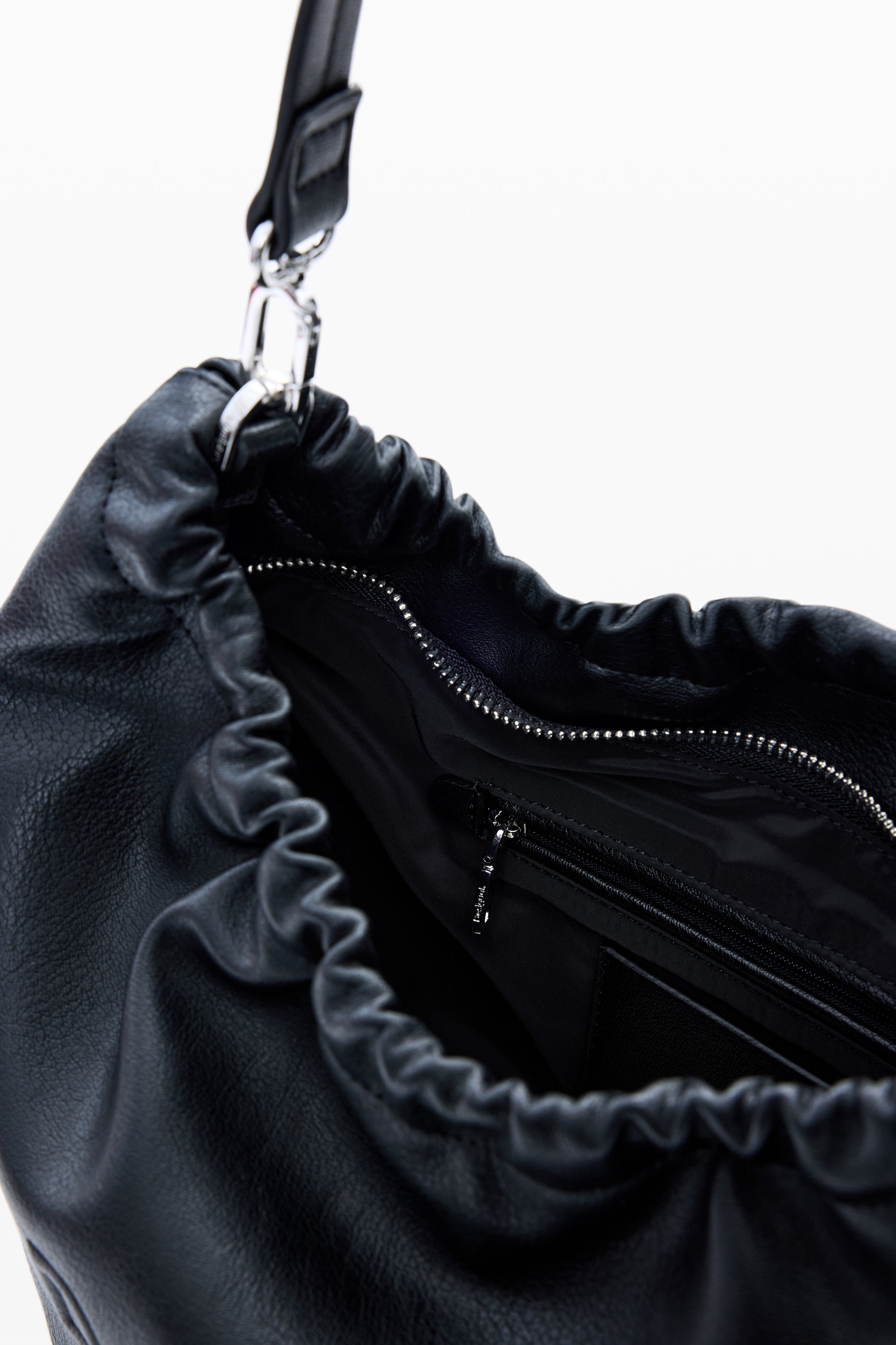 תקריב תיק עור שחור עם רצועת כתף, סגירת שרוך ורוכסן פנימי לאחסון