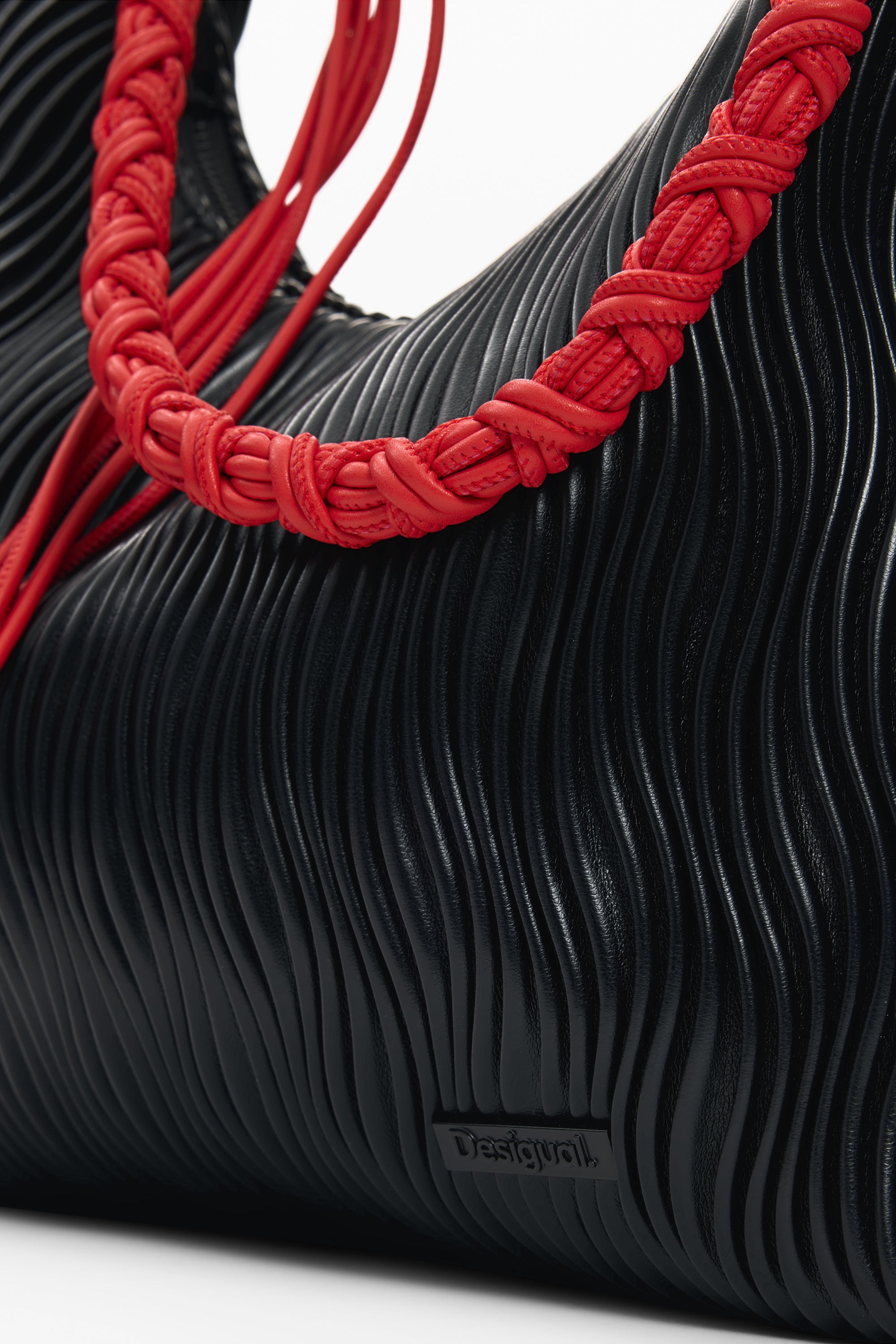 תקריב תיק יד שחור עם טקסטורה גלית וידית קלועה באדום, אופנתי לנשים