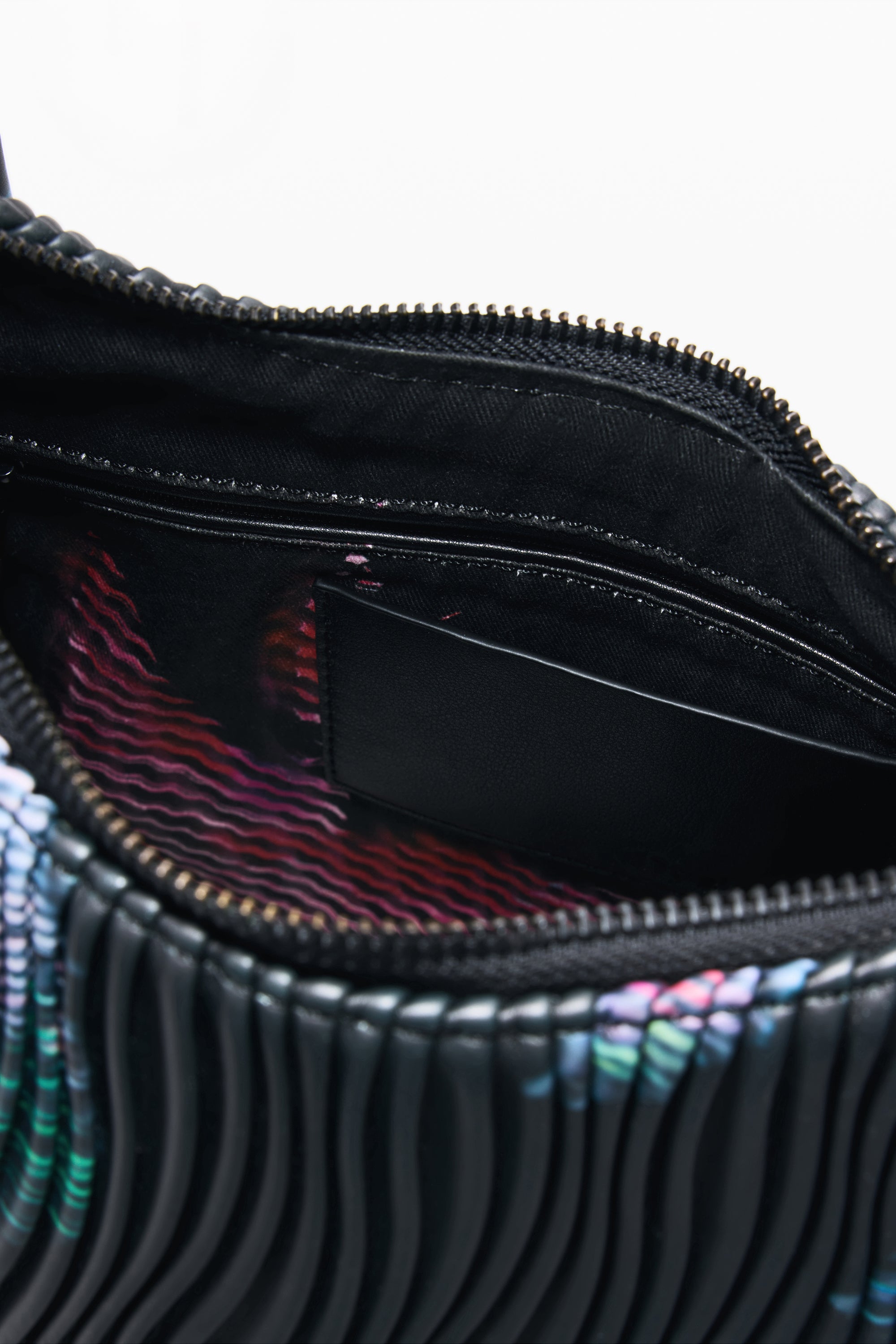 תקריב חלל פנימי של תיק יד עם רוכסן, בטנה צבעונית וכיס פנימי.