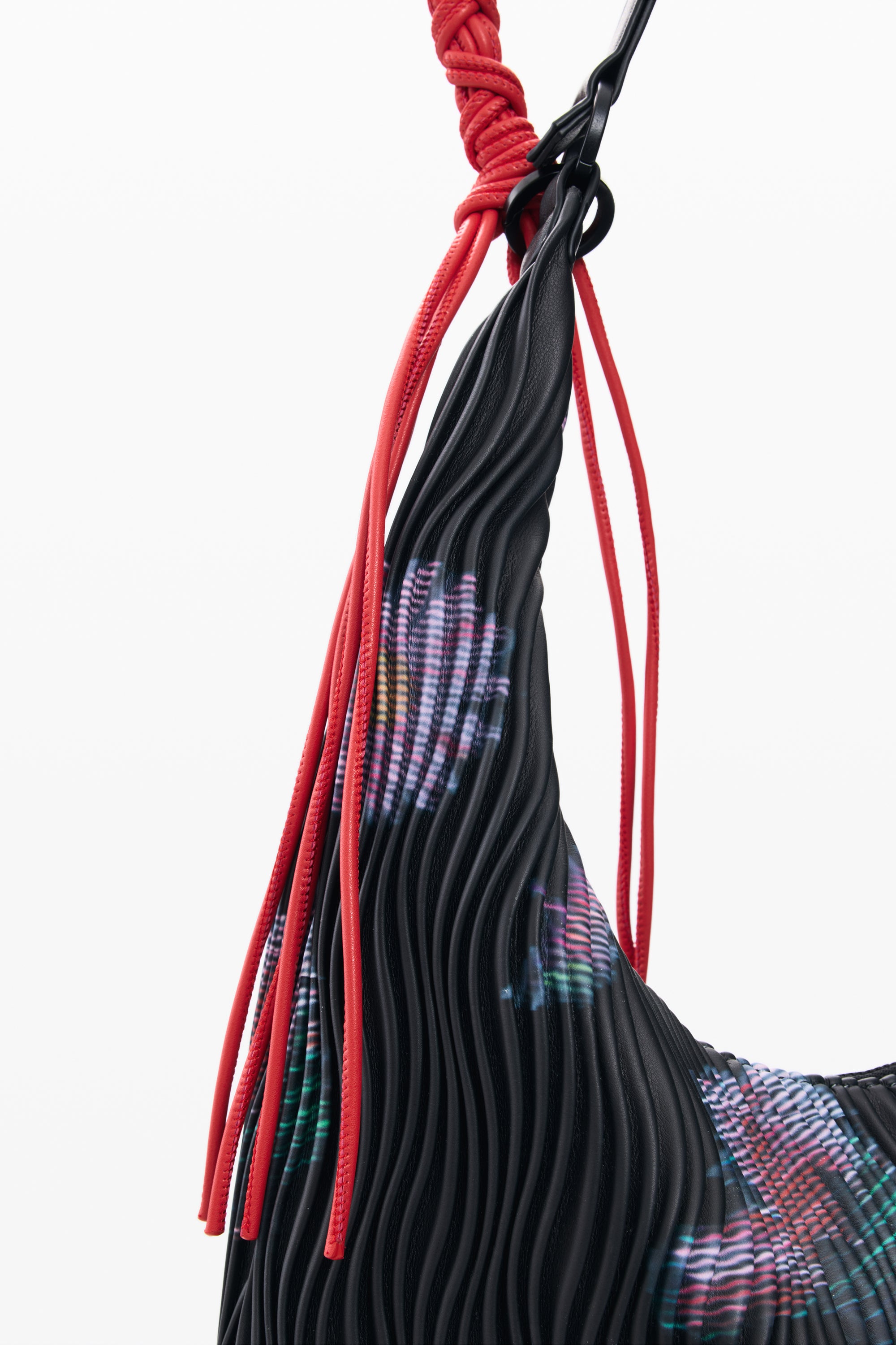 תקריב תיק כתף שחור עם טקסטורה גלי ודוגמת פרח צבעונית, רצועות אדומות מעוצבות