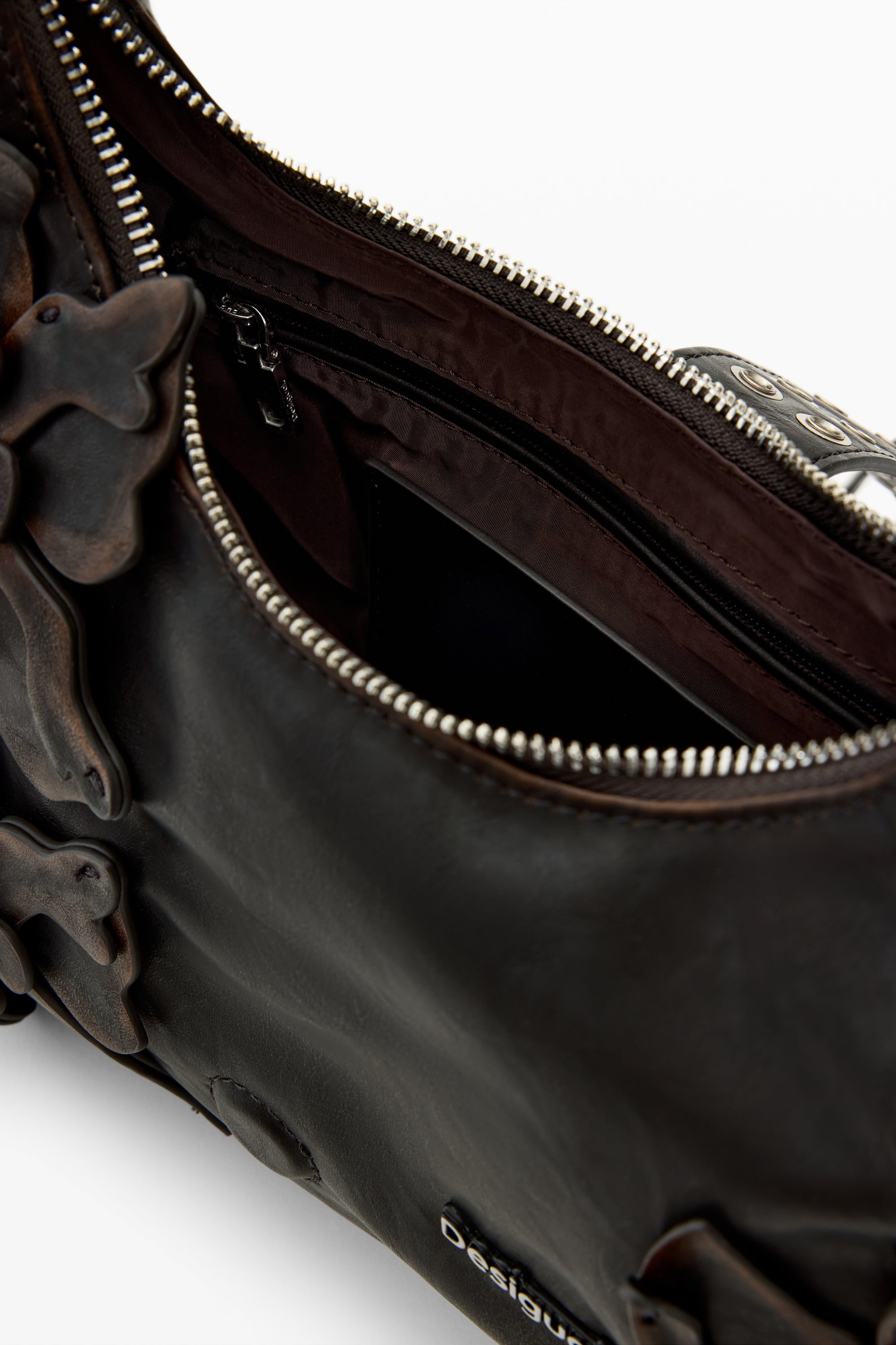 תקריב פנימי של תיק עור חום עם רוכסן פתוח ועיטורים בולטים