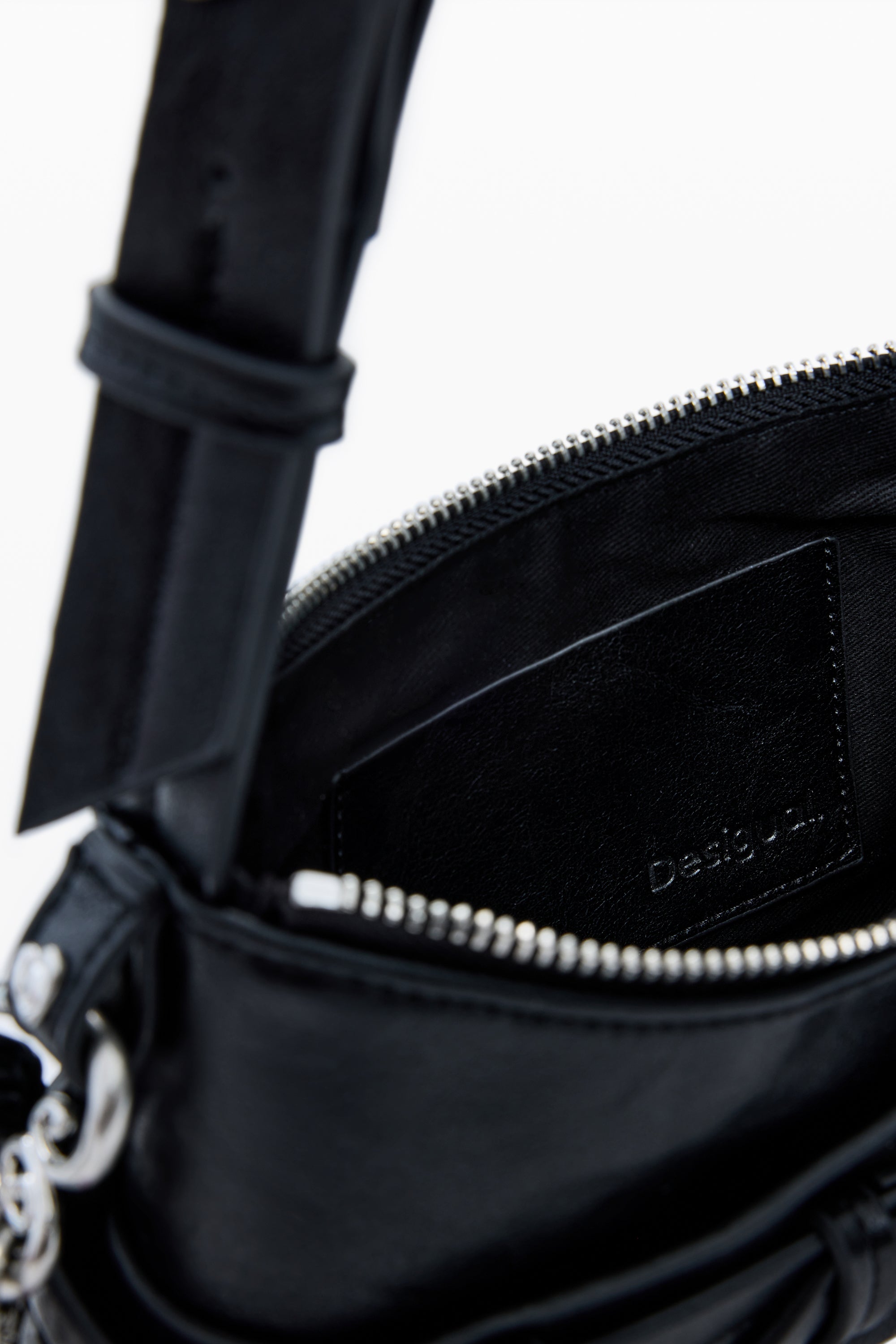 תקריב פנים של תיק עור שחור עם רוכסן פתוח ותג פנימי, עיצוב יוקרתי ואופנתי