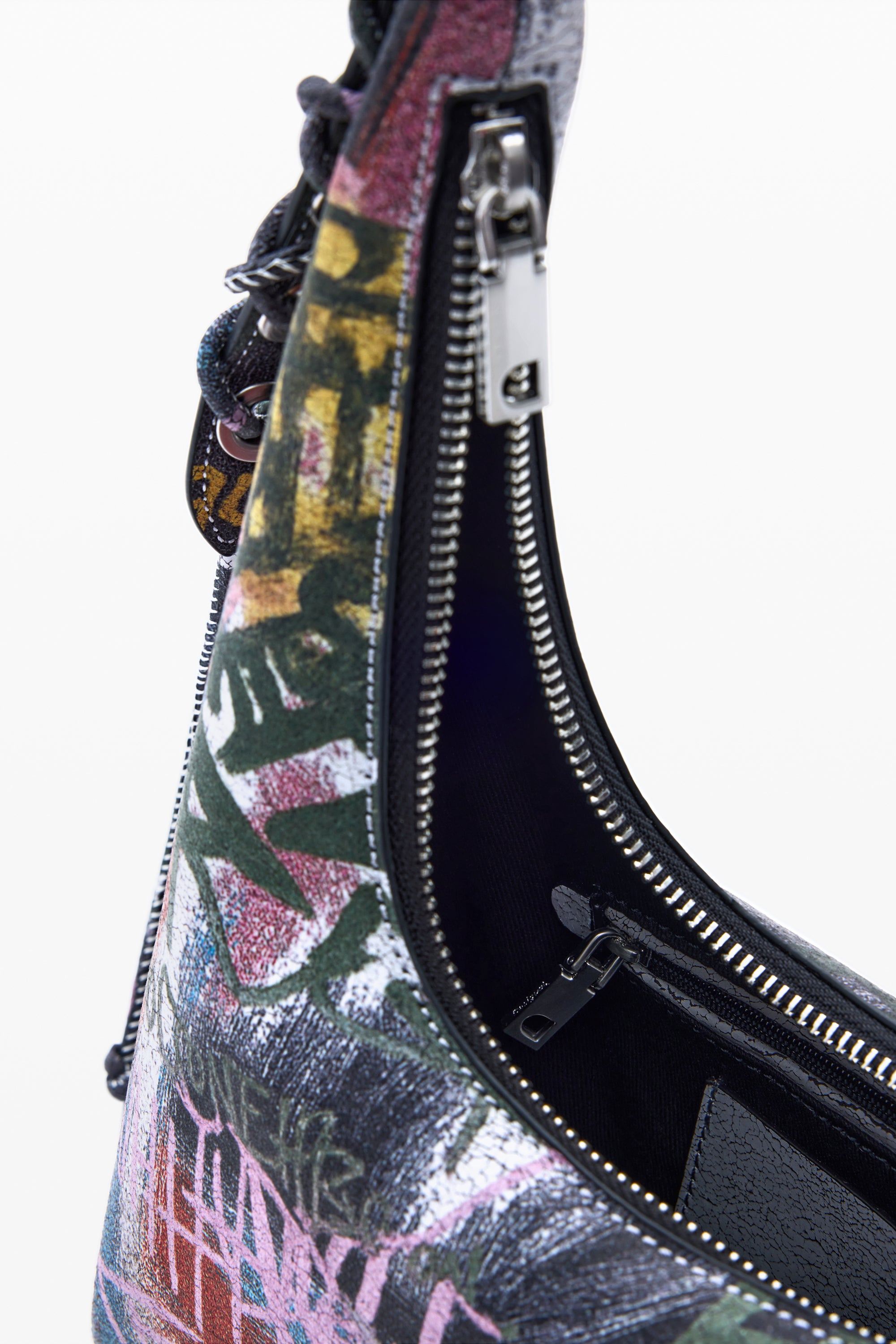 תקריב על תיק צד אופנתי עם דוגמת גרפיטי צבעונית, רוכסנים פתוחים בחזית