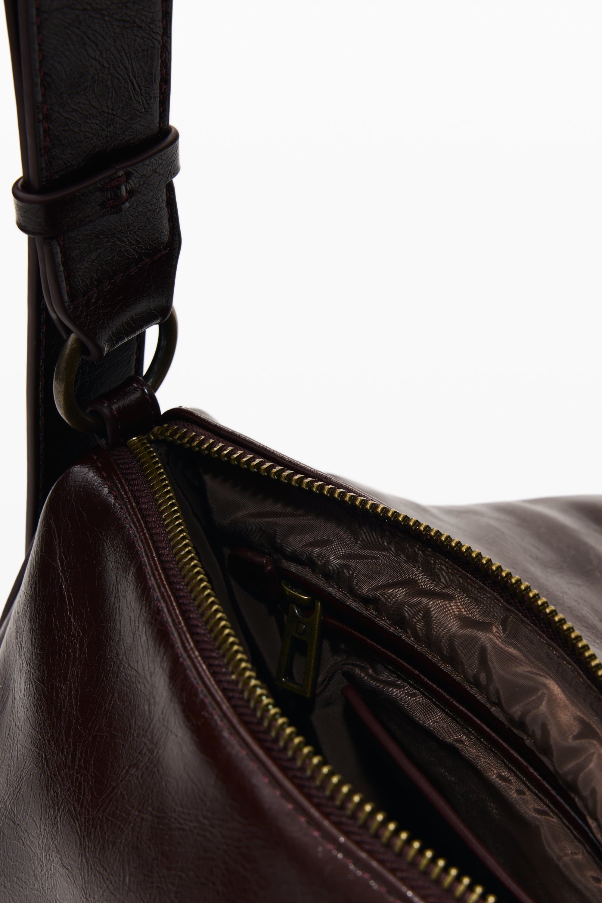 תקריב של תיק עור חום כהה עם רוכסן מתכת פתוח ותא פנימי מרופד