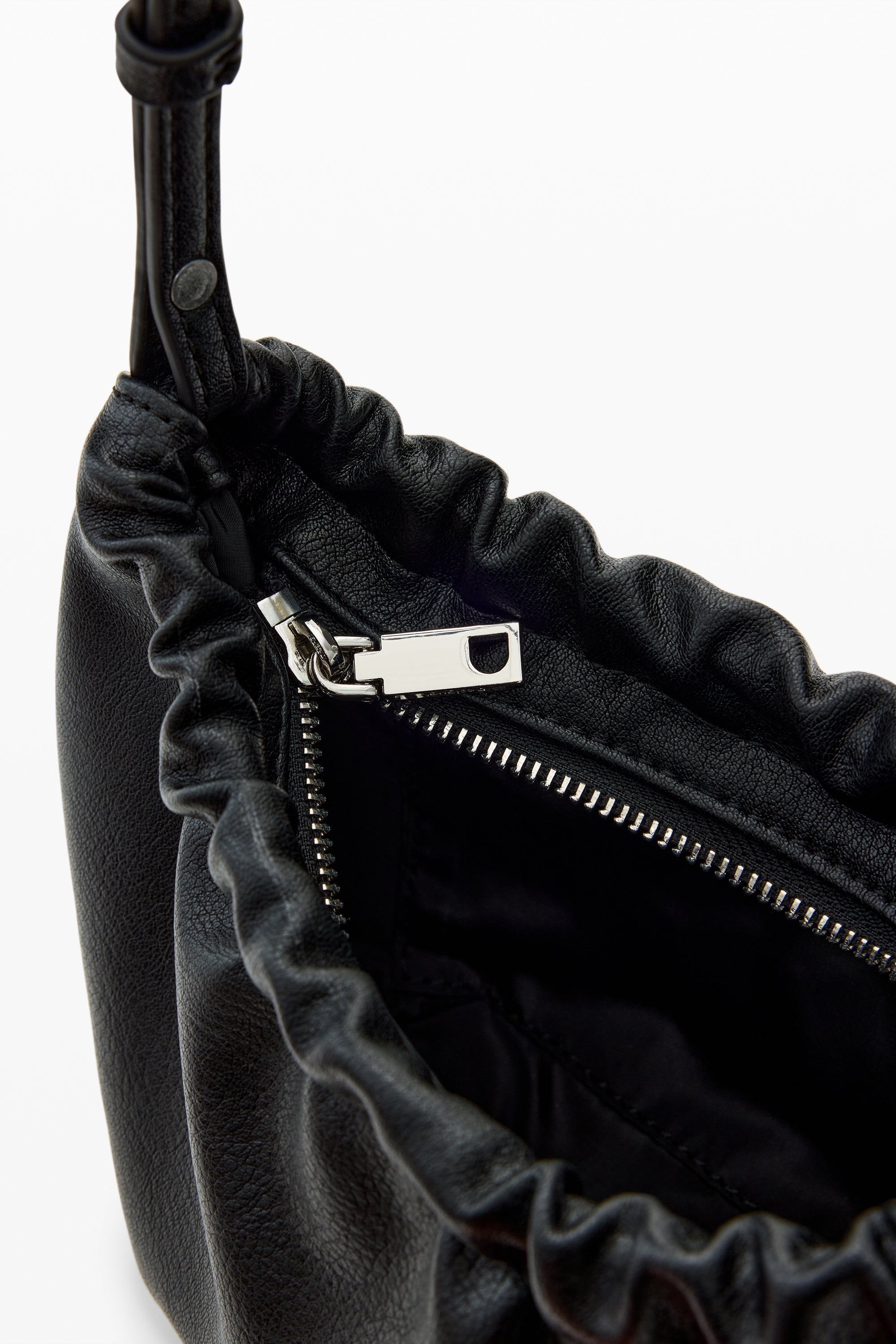 תקריב של תיק יד עור שחור עם רוכסן כסוף ועיצוב קפלים מודרני