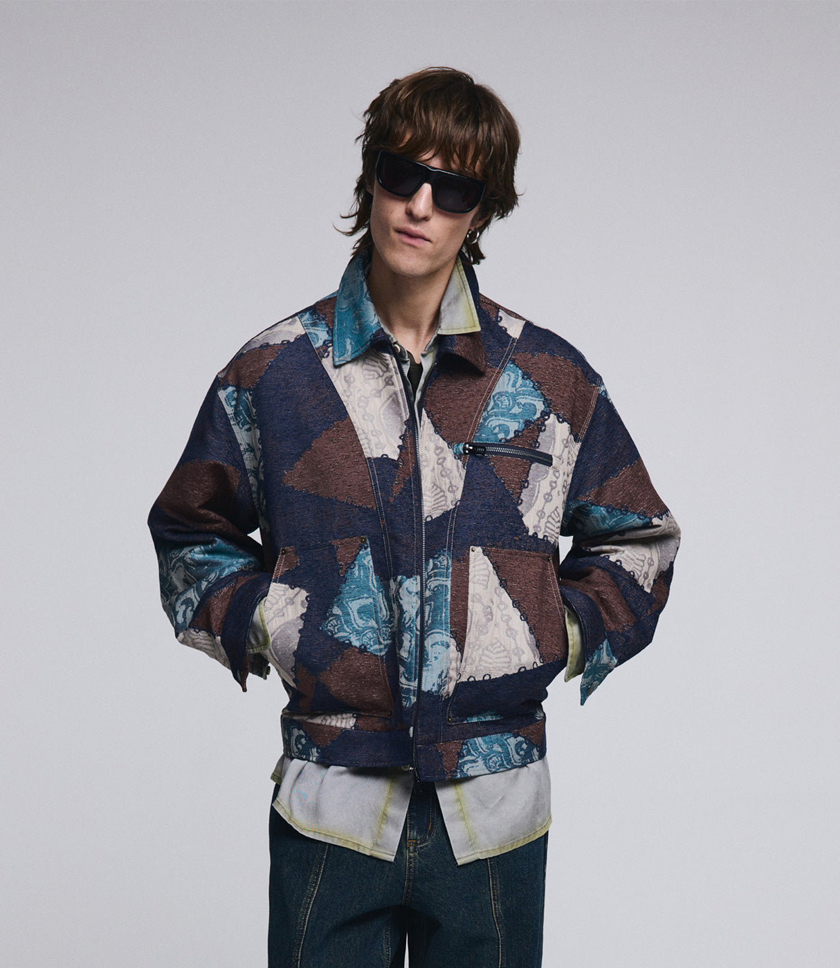 דוגמן עם ז'קט ג'ינס פאטצ'ים צבעוני, משקפי שמש וכפתור רוכסן, אופנה גברית מודרנית