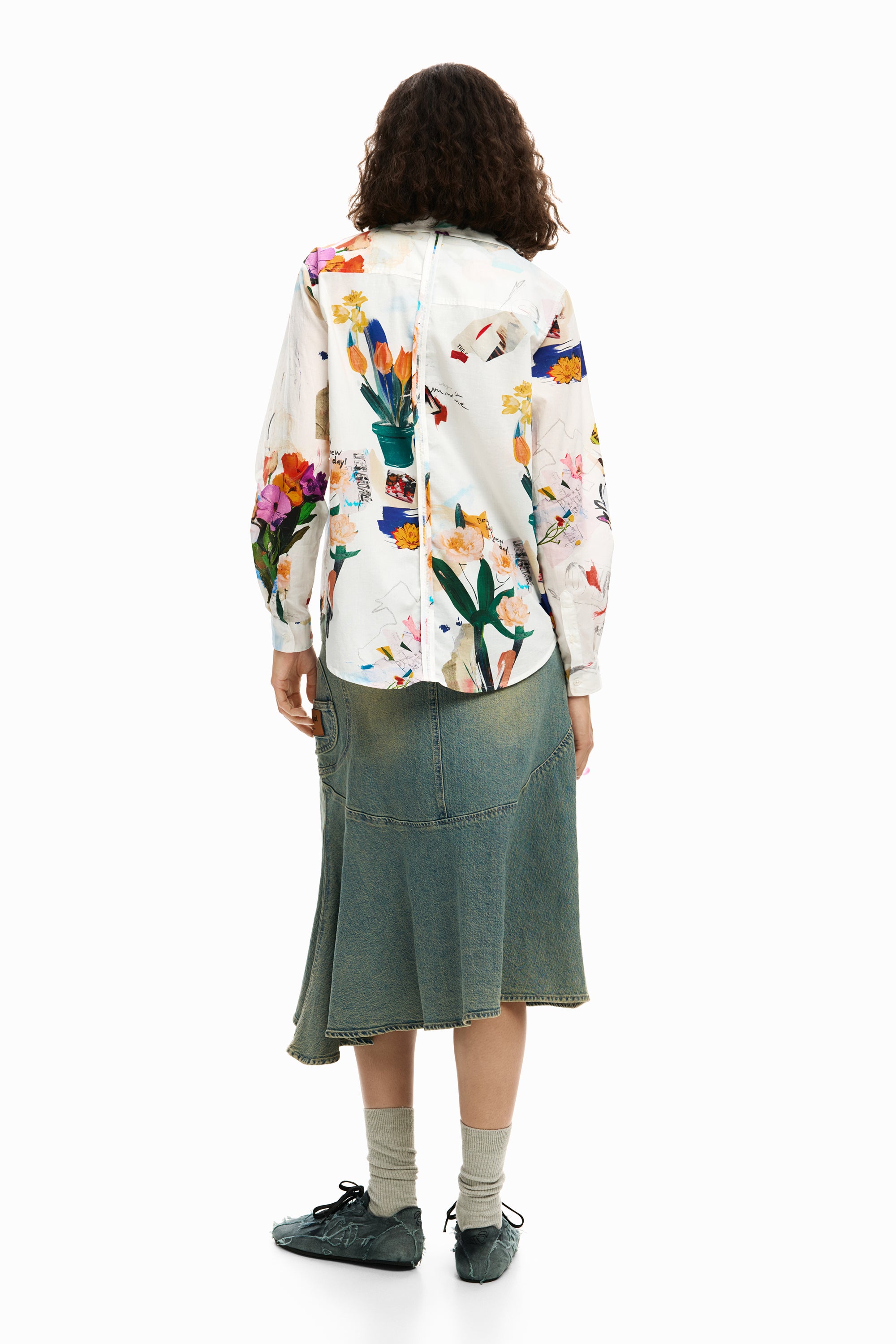 אישה לובשת חולצה לבנה עם הדפס פרחים צבעוני וחצאית ג'ינס, מבט מאחור