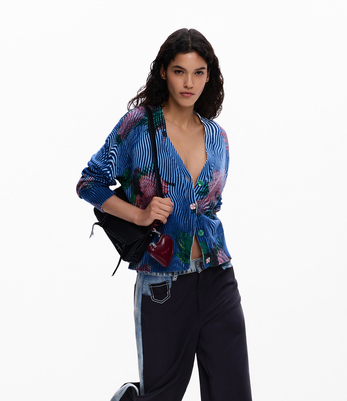 אישה לובשת קרדיגן פסים כחול עם הדפס פרחוני מכופתר, מכנס ג'ינס משולב, ותיק שחור