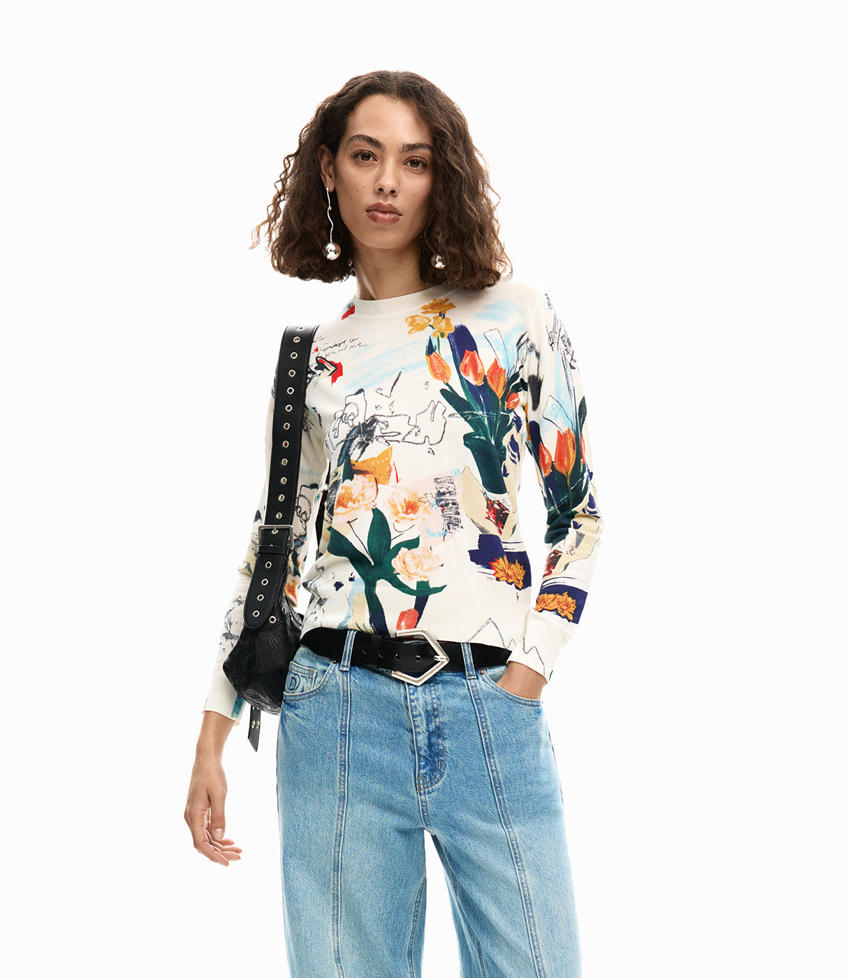 אישה לובשת חולצת דפוס פרחים צבעונית עם שרוולים ארוכים, ג'ינס ותיק צד שחור