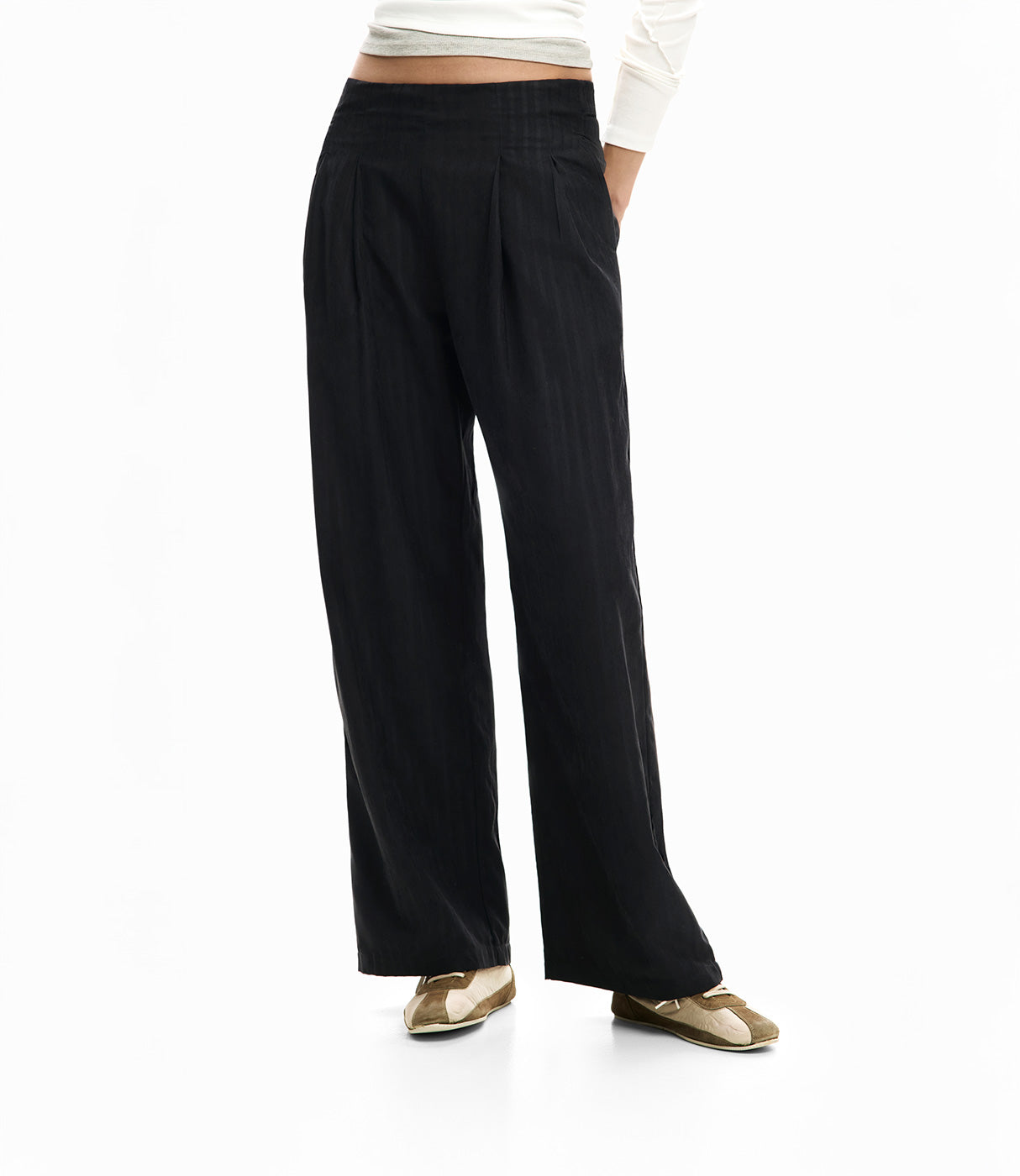 מכנסי נשים רחבים שחורים בגזרה גבוהה, בד קליל, משולבים עם חולצה לבנה ונעליים שטוחות