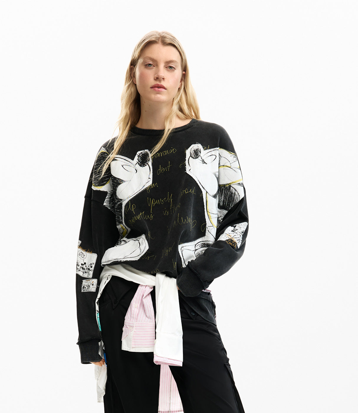 אישה לובשת סווטשירט שחור עם הדפס איורים ודמויות מצוירות, מראה אופנתי מודרני