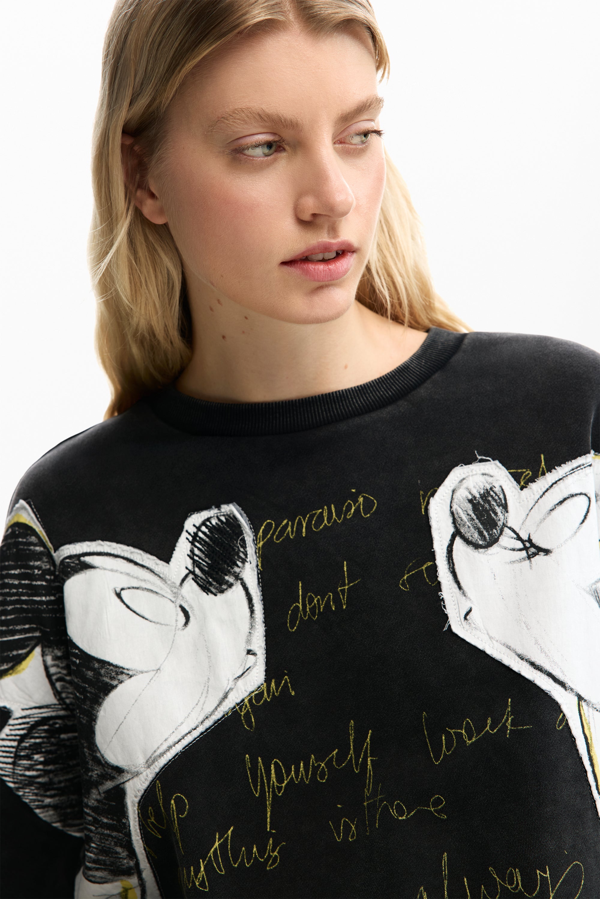 אישה לובשת סווטשרט שחור עם הדפס ציורים לבנים וכתובים באנגלית