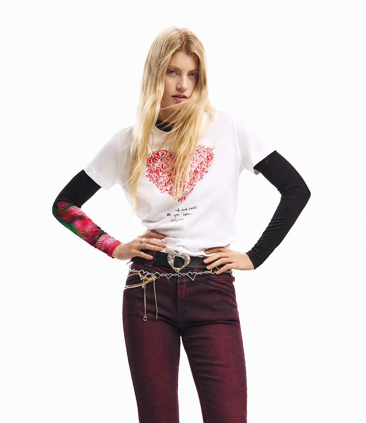 דוגמנית בלבוש אופנתי: חולצת טי לבנה עם הדפס לב אדום, מכנסי ג'ינס בורדו, שרשרת ותוספות צבעוניות לסטיילינג ייחודי