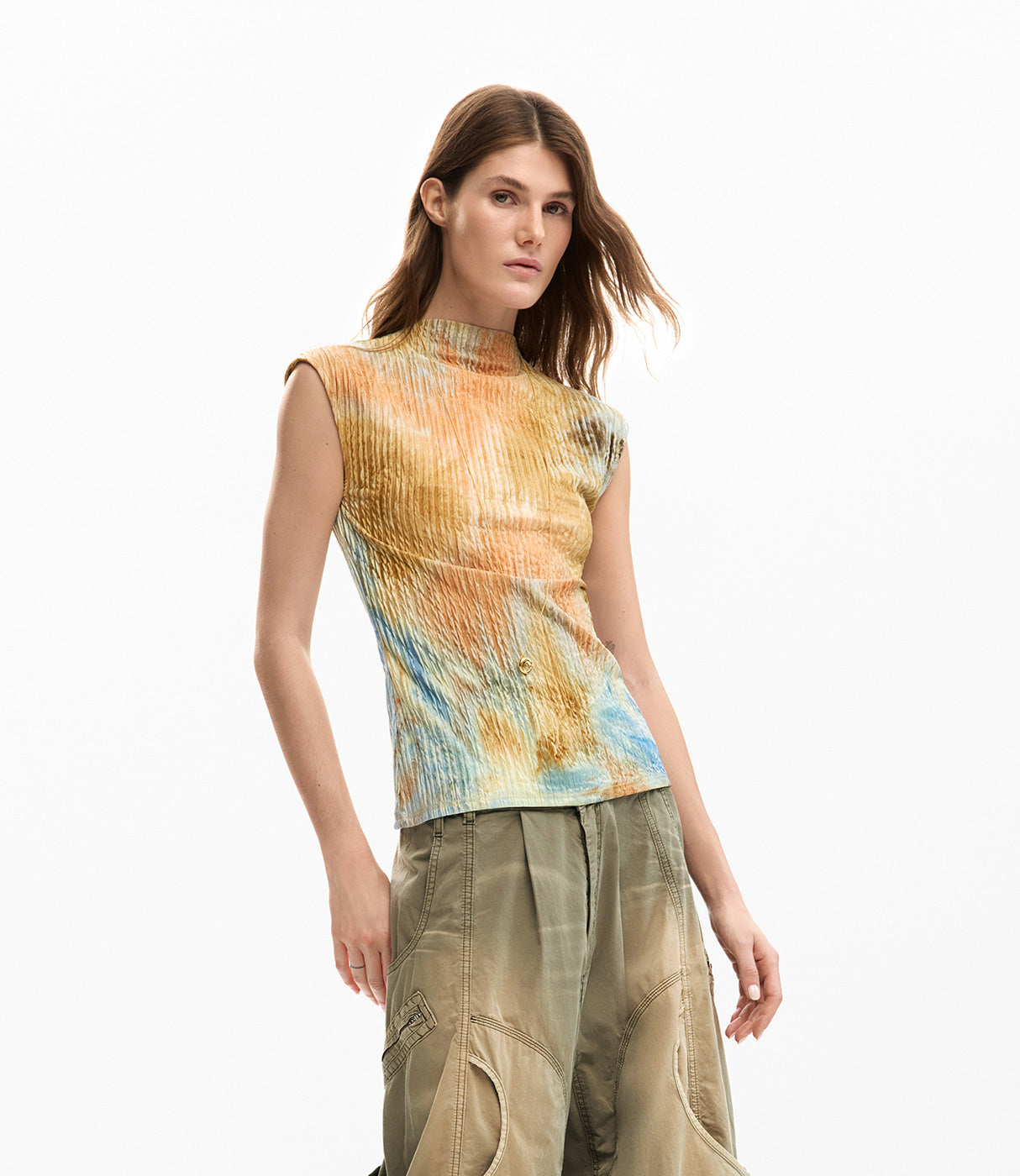 אישה לובשת חולצה צמודה צבעונית ללא שרוולים עם צווארון גבוה ומכנסיים ירוקים רחבים, אופנת קיץ נשים