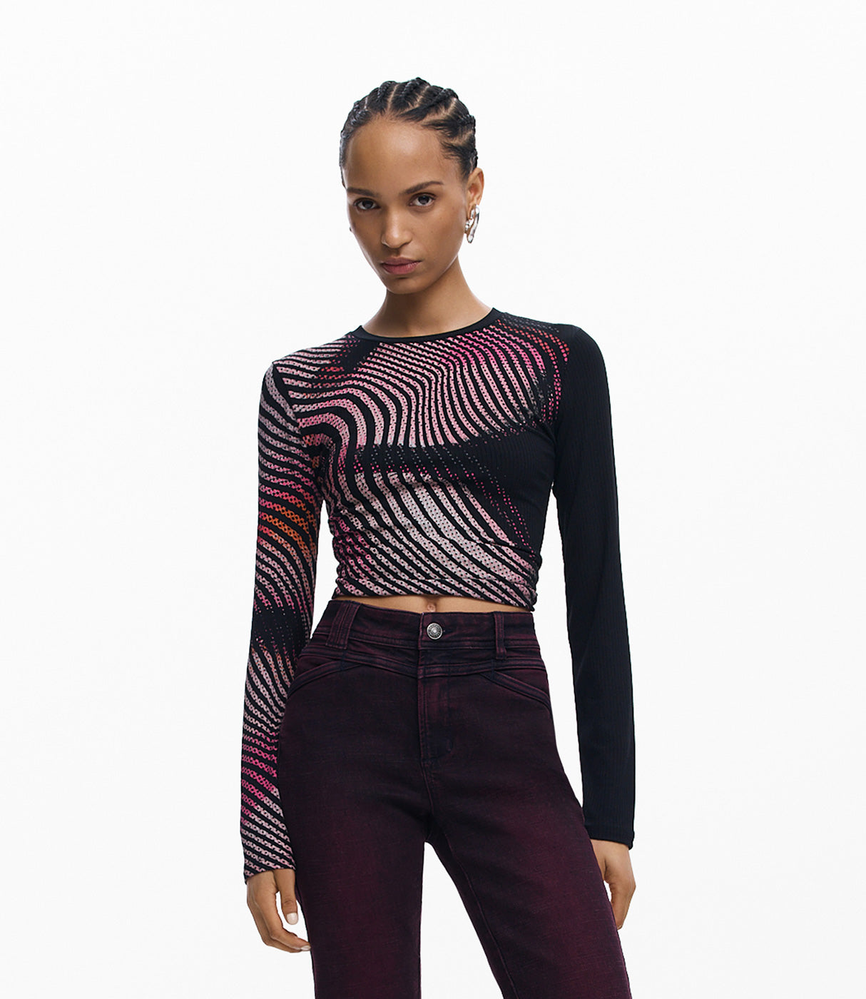 אישה לובשת חולצת שרוול ארוך שחורה עם דוגמת פסים סגלגלה ומכנסיים כהים