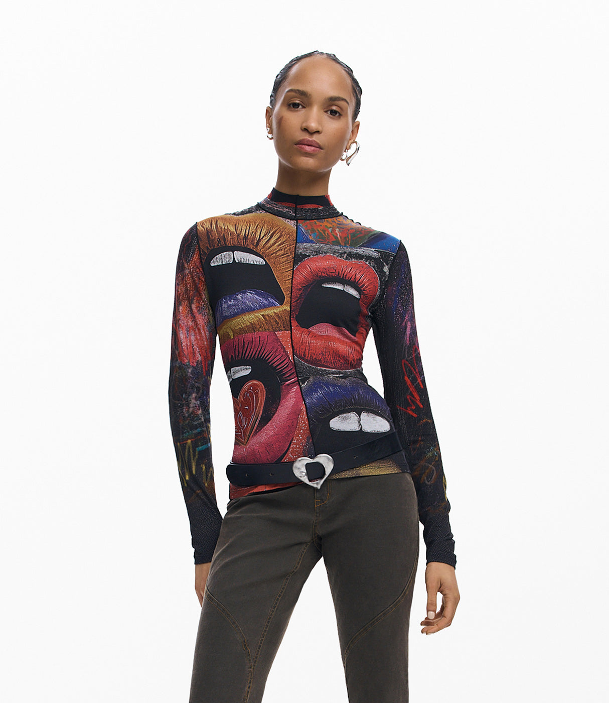 אישה עם חולצת גולף שרוולים ארוכים בדפוס שפתיים צבעוני ומכנסיים כהים, רקע לבן