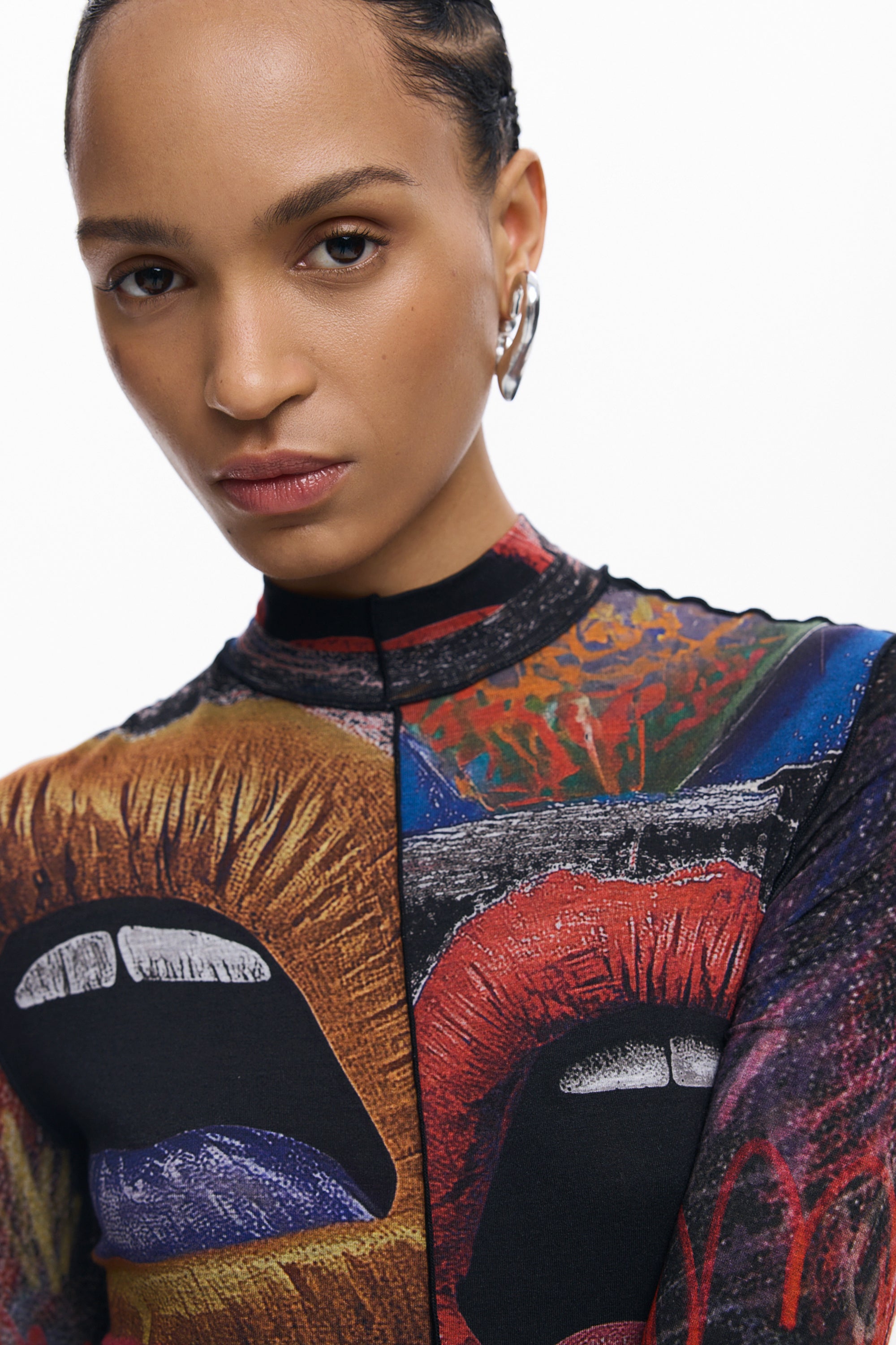 אישה עם עגיל כסף לובשת חולצה צבעונית בהדפס שפתיים גרפי, רקע לבן, אופנת נשים מודרנית