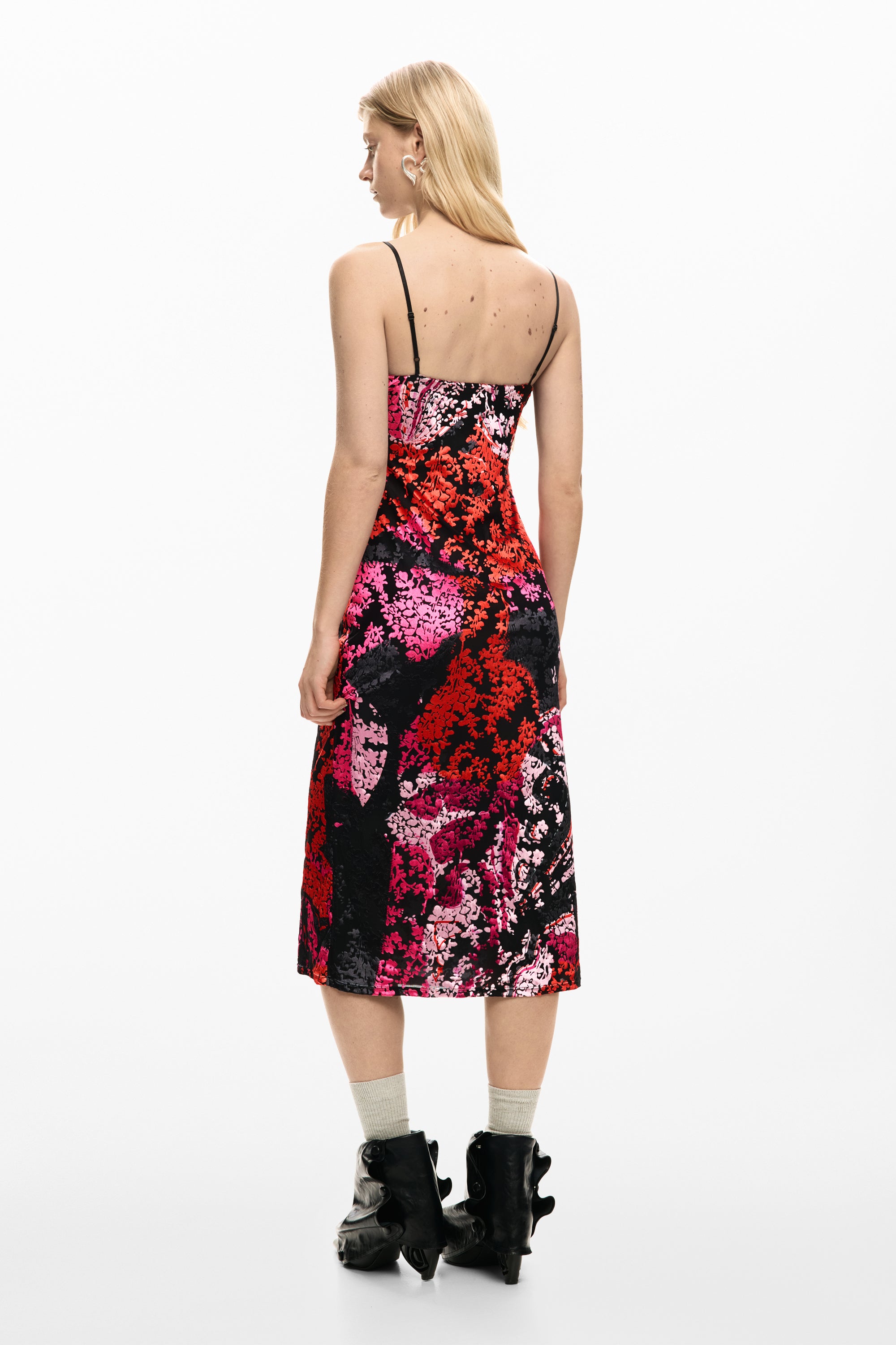 אישה בשמלת קיץ פרחונית עם כתפיות דקות בצבעי ורוד, אדום ושחור, נעלי עקב שחורות ייחודיות