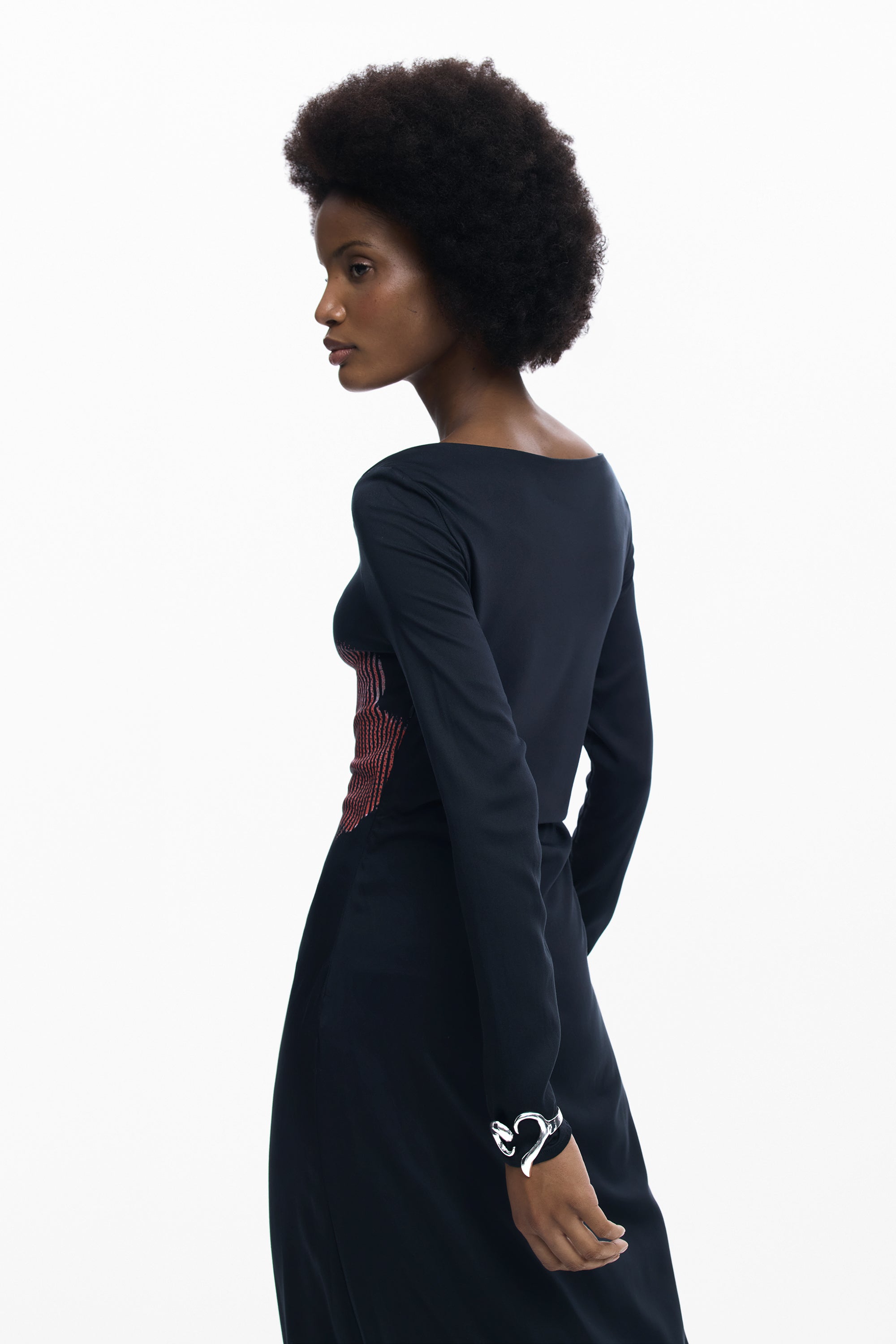 אישה לובשת שמלה שחורה ארוכה עם שרוולים ארוכים ועיצוב ייחודי באזור המותניים