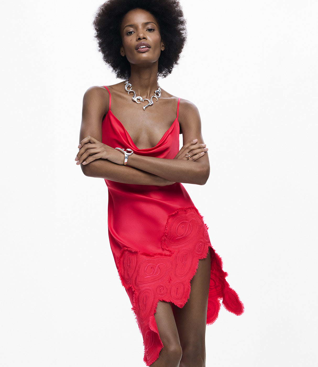 אישה לובשת שמלת סאטן אדומה עם כתפיות דקות ועיטורי תחרה, על רקע לבן