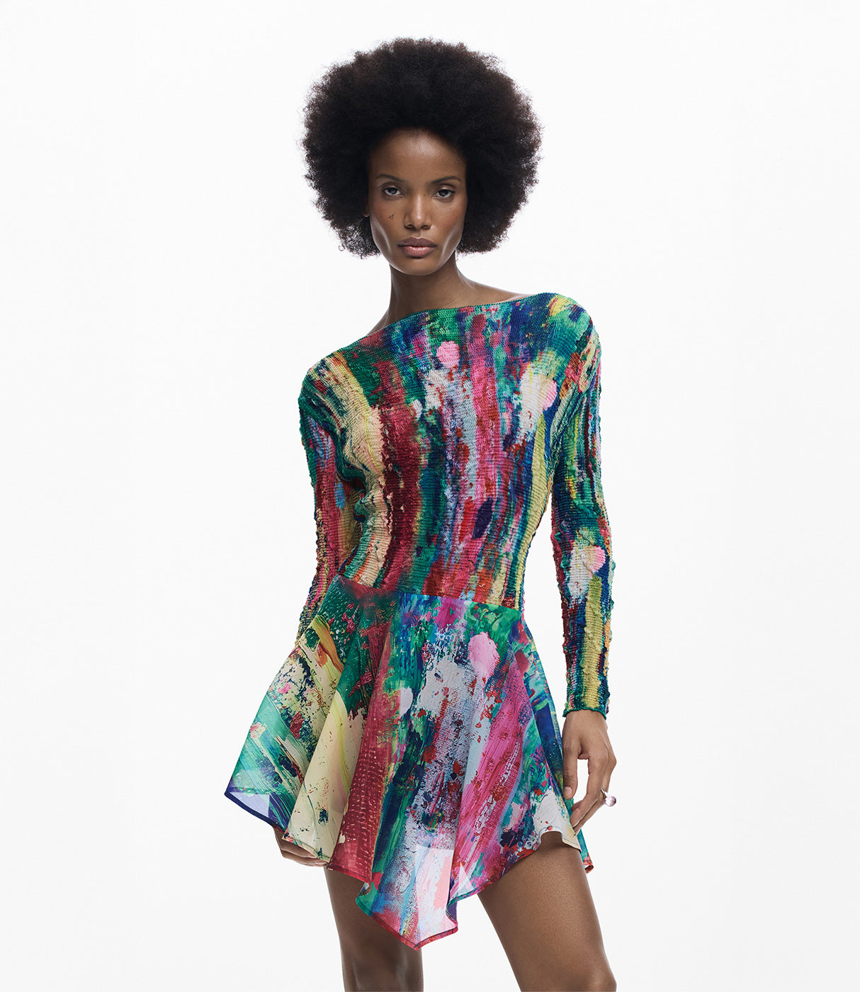 אישה לובשת שמלת מיני צבעונית עם שרוולים ארוכים ודוגמת ציור מופשט, רקע לבן