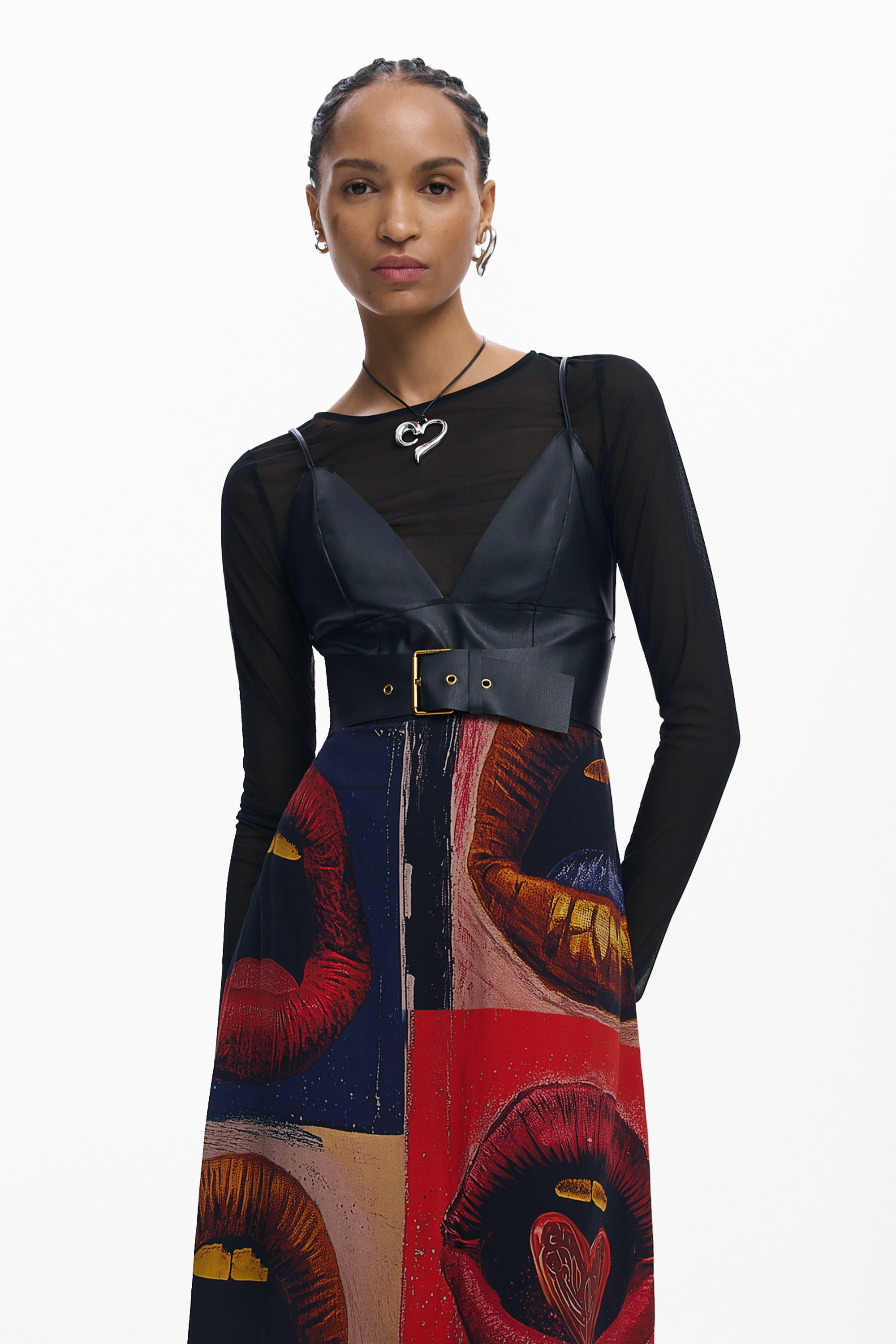 אישה לובשת שמלת מקסי עם דפוס שפתיים צבעוני, טופ שחור ועגילי טבעת, על רקע לבן