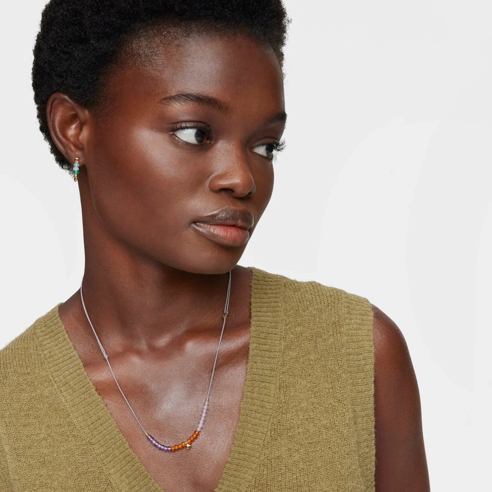 דוגמנית עונדת שרשרת צבעונית ועגיל תואם, רקע לבן, אופנת תכשיטים CHOZEN