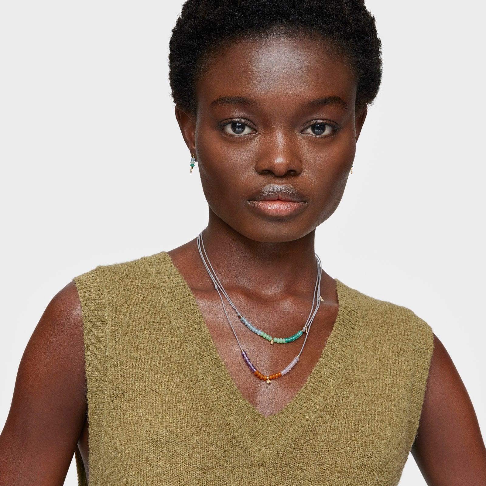 דוגמנית עם שרשראות חרוזים צבעוניות, חולצת סריג ירוקה, צילום לאתר CHOZEN