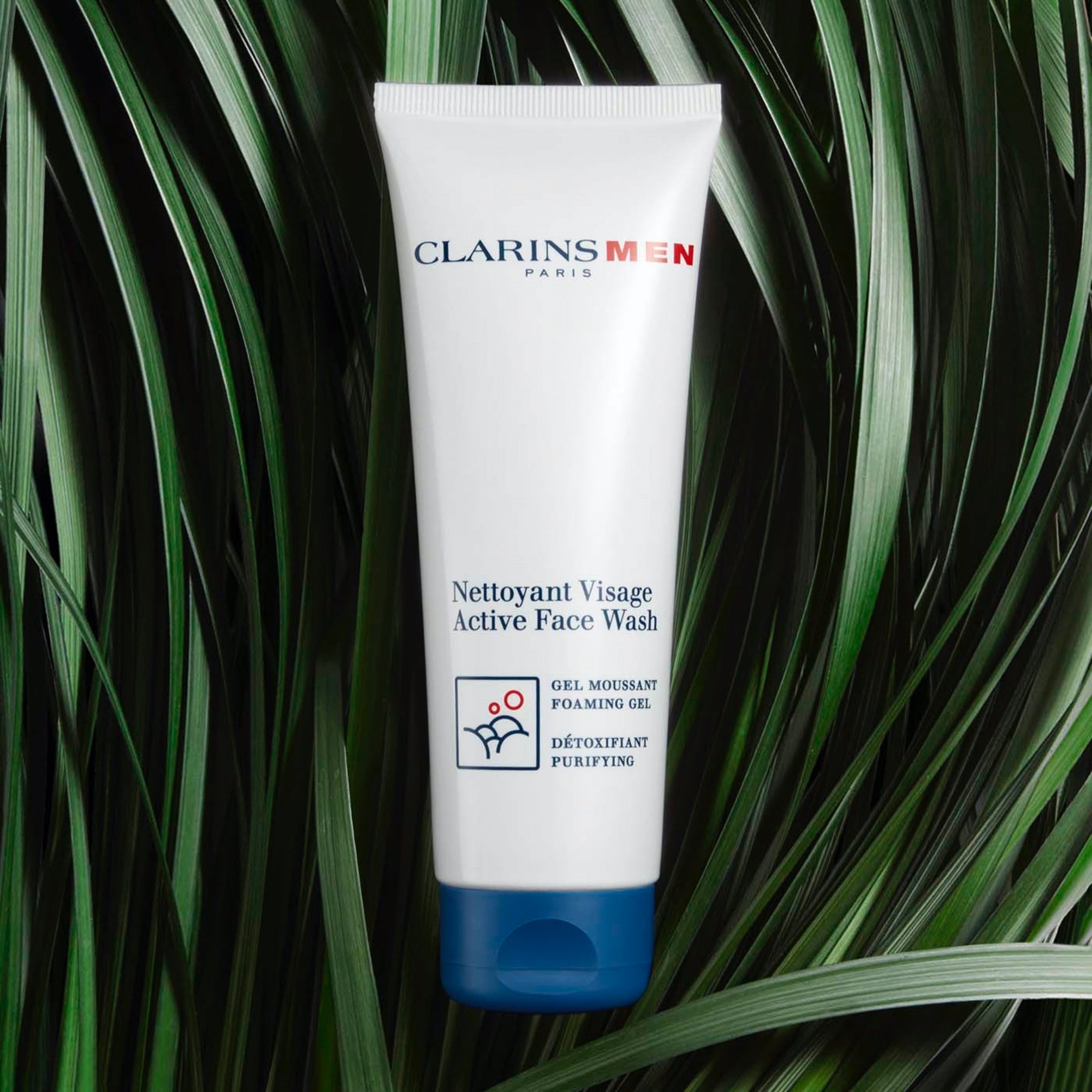 ג'ל ניקוי פנים לגברים Clarins Men על רקע עלים ירוקים, מוצר טיפוח לפנים