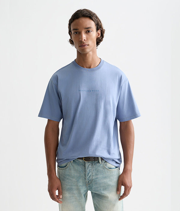 דגם לבוש בחולצת טי כחולה של Scotch & Soda וג'ינס, מצולם רקע לבן ל-CHOZEN