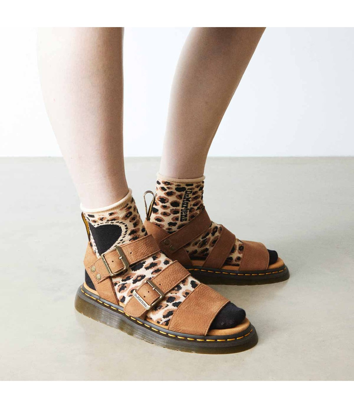 סנדלי DR. MARTENS Gryphon על רגלי אישה עם גרביים מנומר, מבט קדמי אורבני, מבית CHOZEN