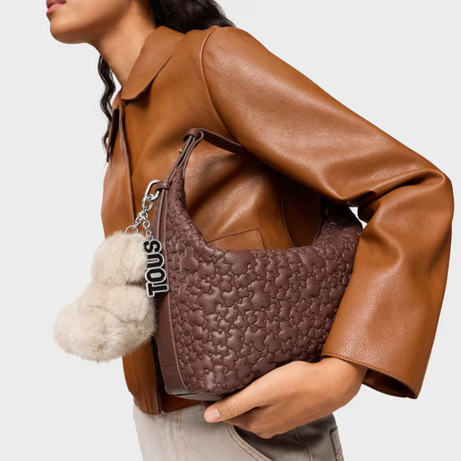 תיק כתף חום מעוצב עם קישוט פרוותי מחזיק מפתחות TOUS, על רקע דגם עם ז'קט עור חום, CHOZEN מותגים מובילים