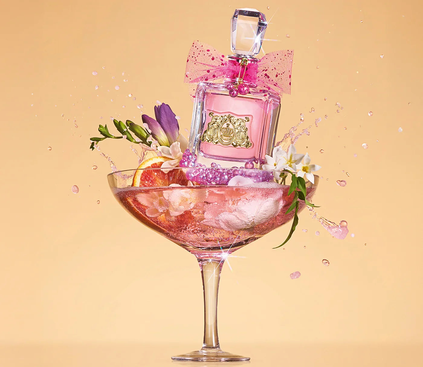 בקבוק בושם ורוד עם פקק קריסטל, קשת ורודה וקישוטים בפרחים וכוס קוקטייל