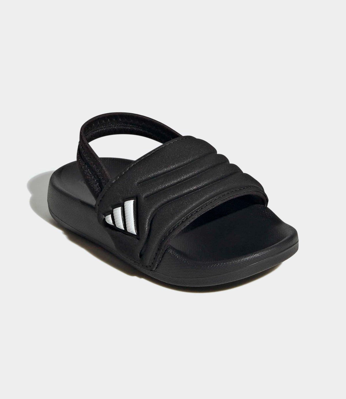 סנדל ספורט לילדים בצבע שחור עם רצועת עקב ולוגו לבן, מונח על רקע אפור