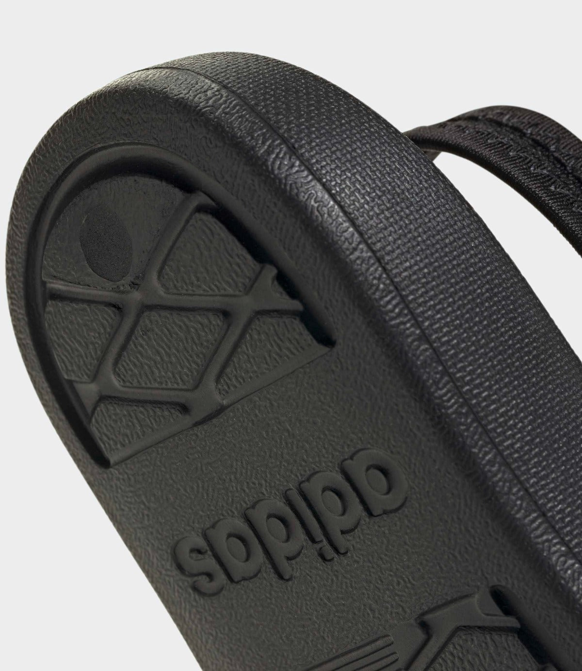 סנדל אצבע שחור עם סוליה טקסטורה ותחתית ממותגת, צילום מקרוב