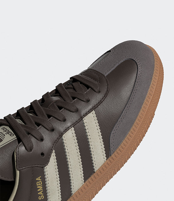 נעל ספורט אופנתית בצבע חום כהה עם שלושה פסים לבנים וסוליה חומה