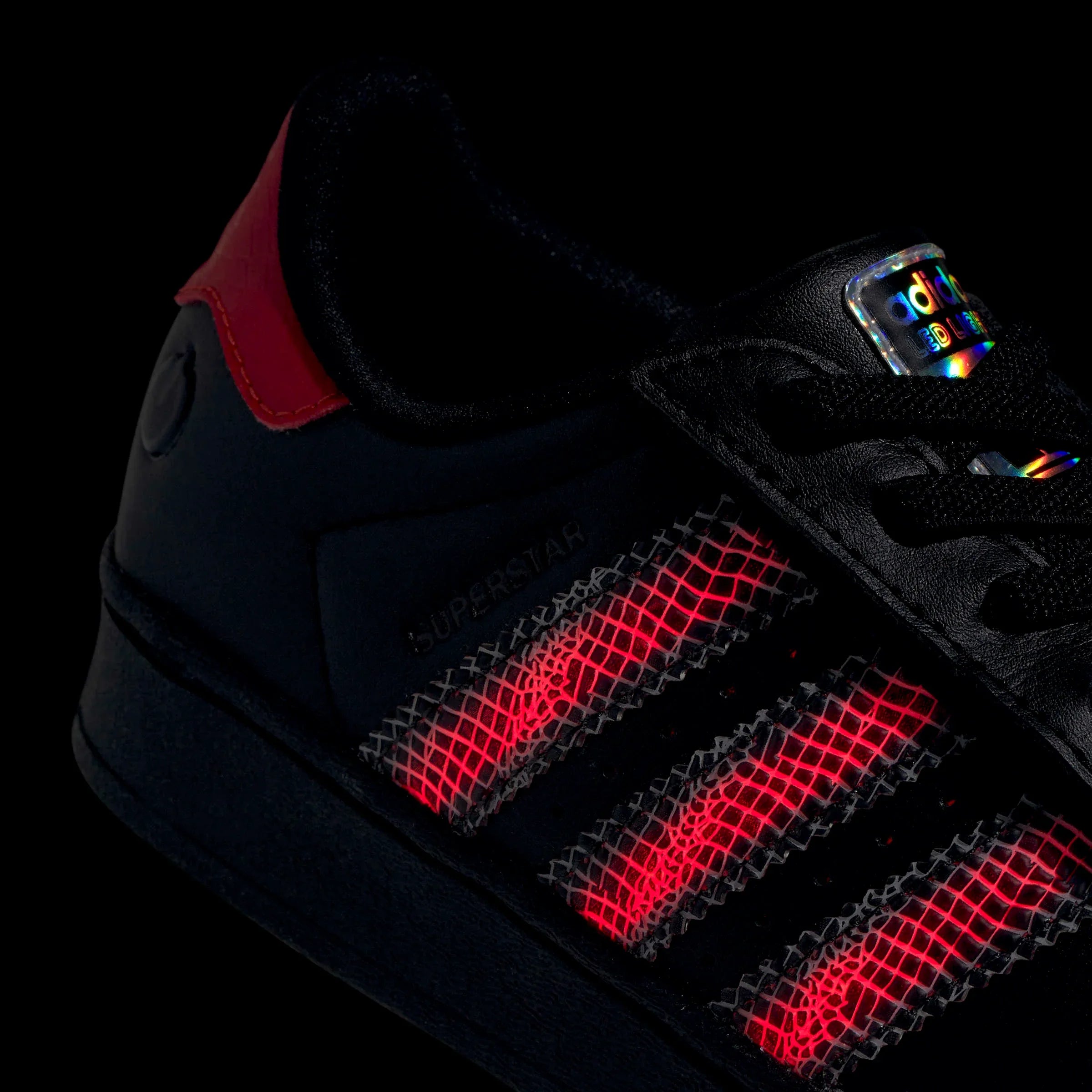 נעל אדידס שחורה עם אלמנטים מחזירי אור ודוגמת אדום מוארת, מאוסף המותגים CHOZEN