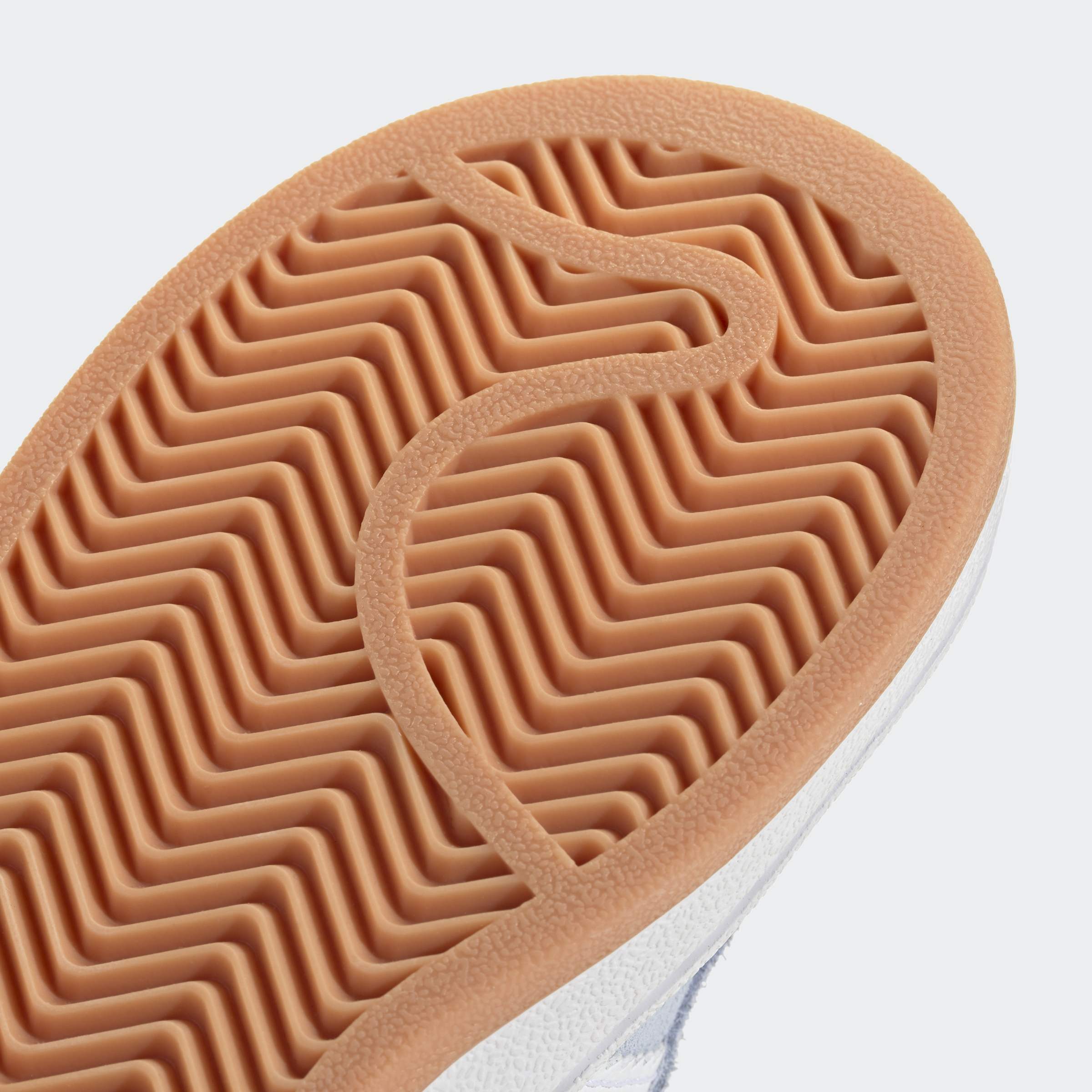 סוליית נעל ספורט בצבע חום עם דוגמת זיגזג, צילום תקריב על רקע לבן
