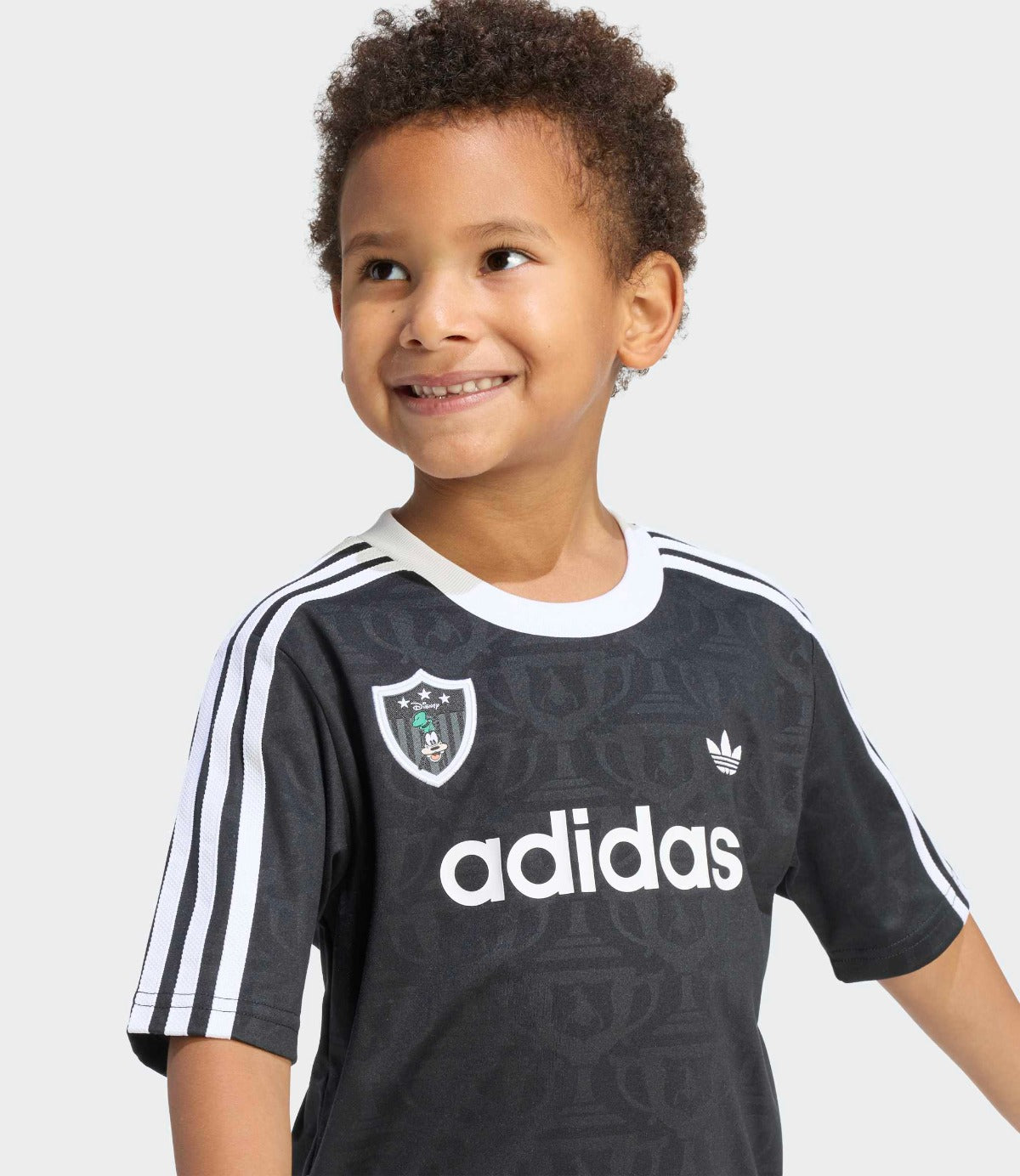 ילד לובש חולצת ספורט שחורה עם שרוולים קצרים, פסים לבנים ולוגו adidas