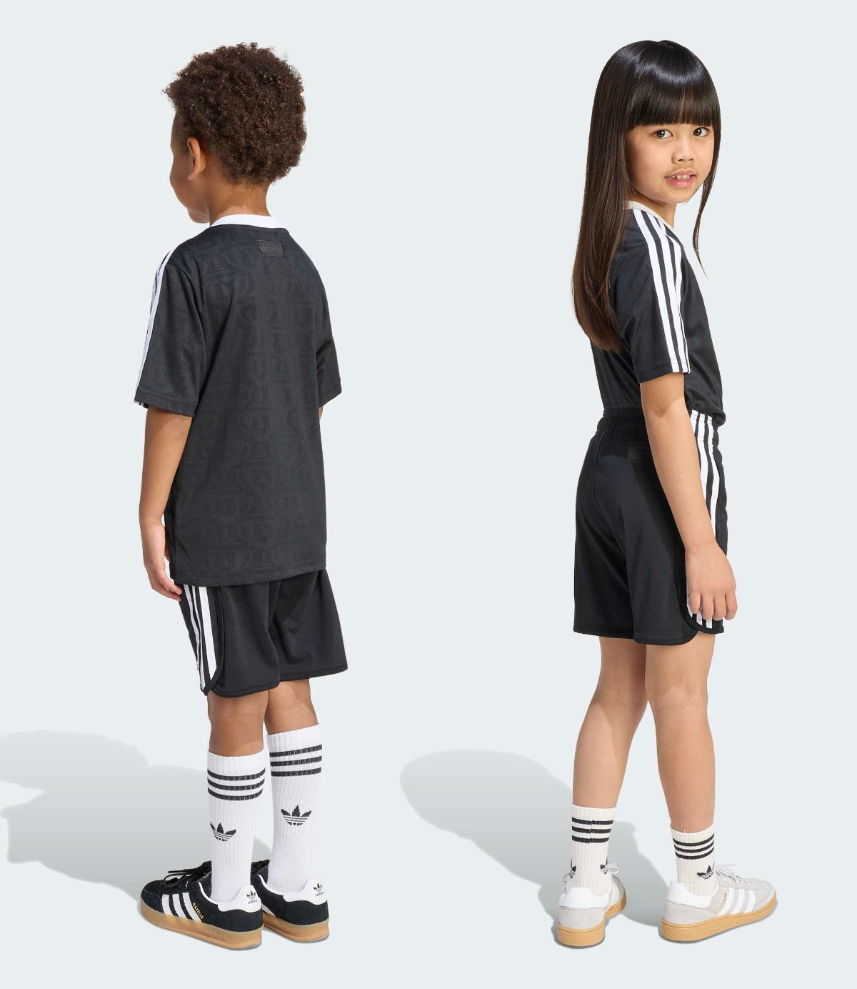 שני ילדים לובשים חולצה ומכנסיים ספורט שחורים עם פסי צד לבנים ונעלי ספורט, מבט מצד ומאחור