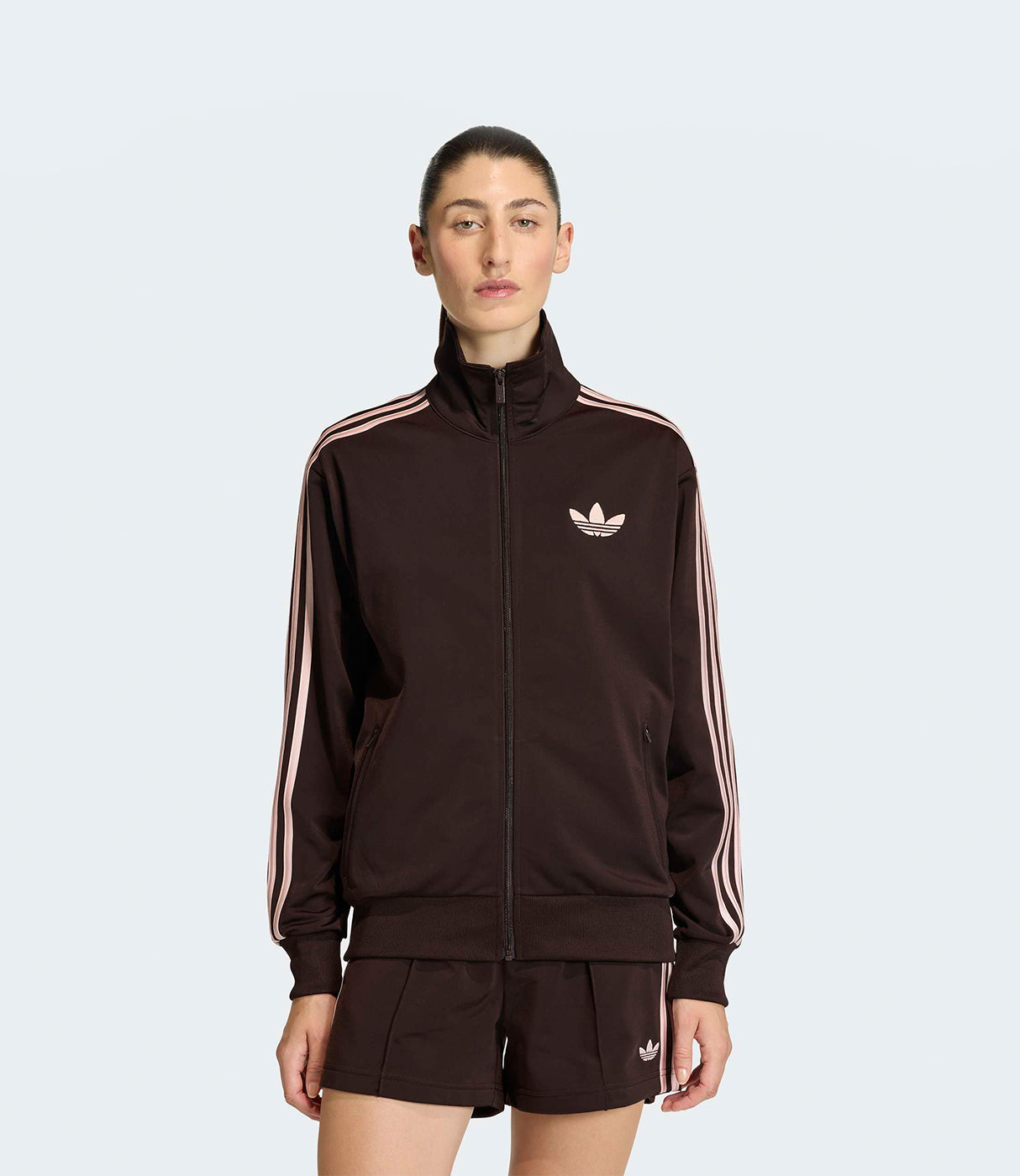 אישה לובשת סט ספורט נשים בצבע חום כהה עם פסים ורודים, דגם קלאסי עם רוכסן