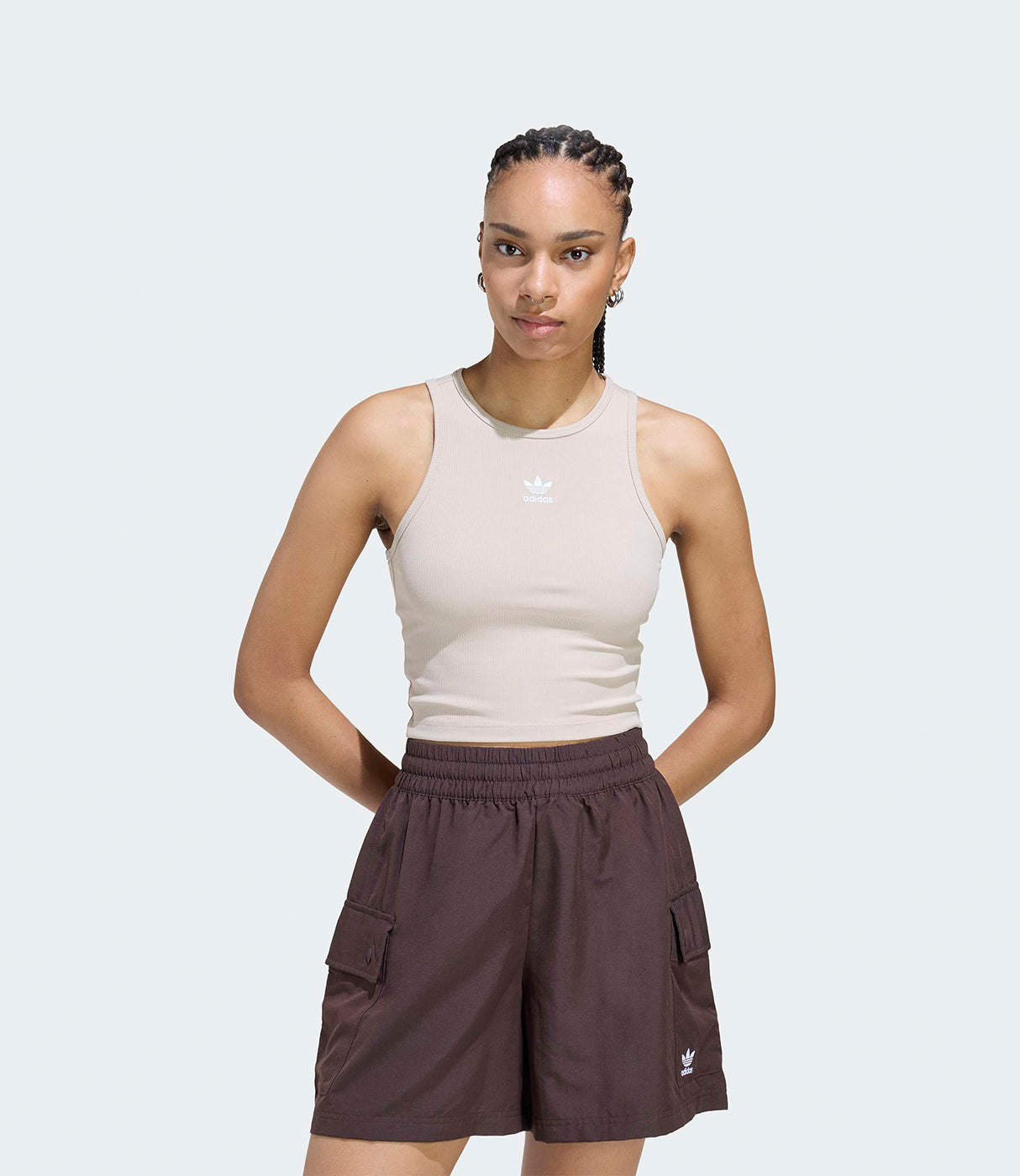 אישה לובשת גופיה בז׳ עם לוגו וחולצת שורטס חומה, אופנת קיץ לנשים