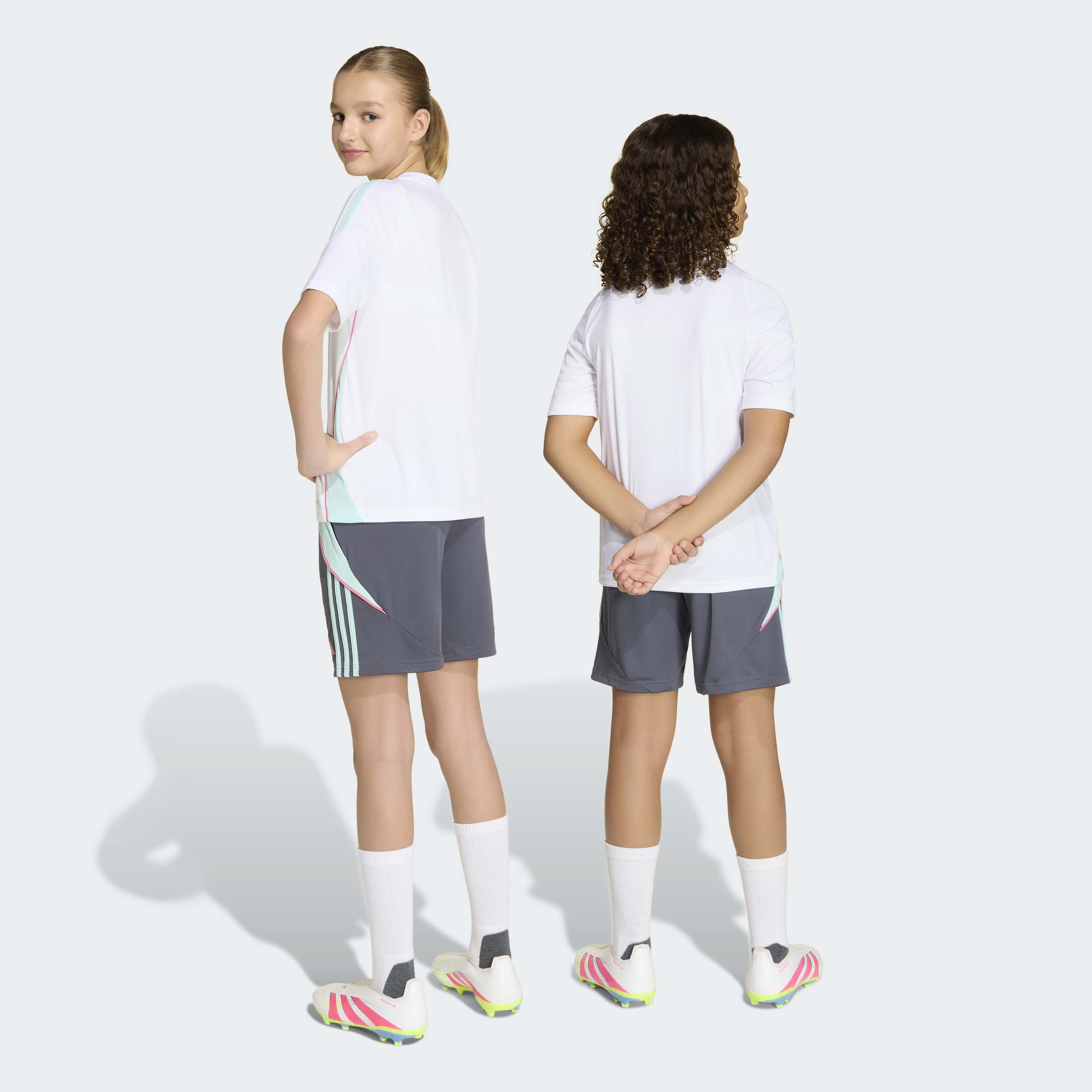 שני ילדים לובשים חולצת ספורט לבנה ומכנסיים קצרים אפורים, נעלי כדורגל לבנות וגרביים ארוכים