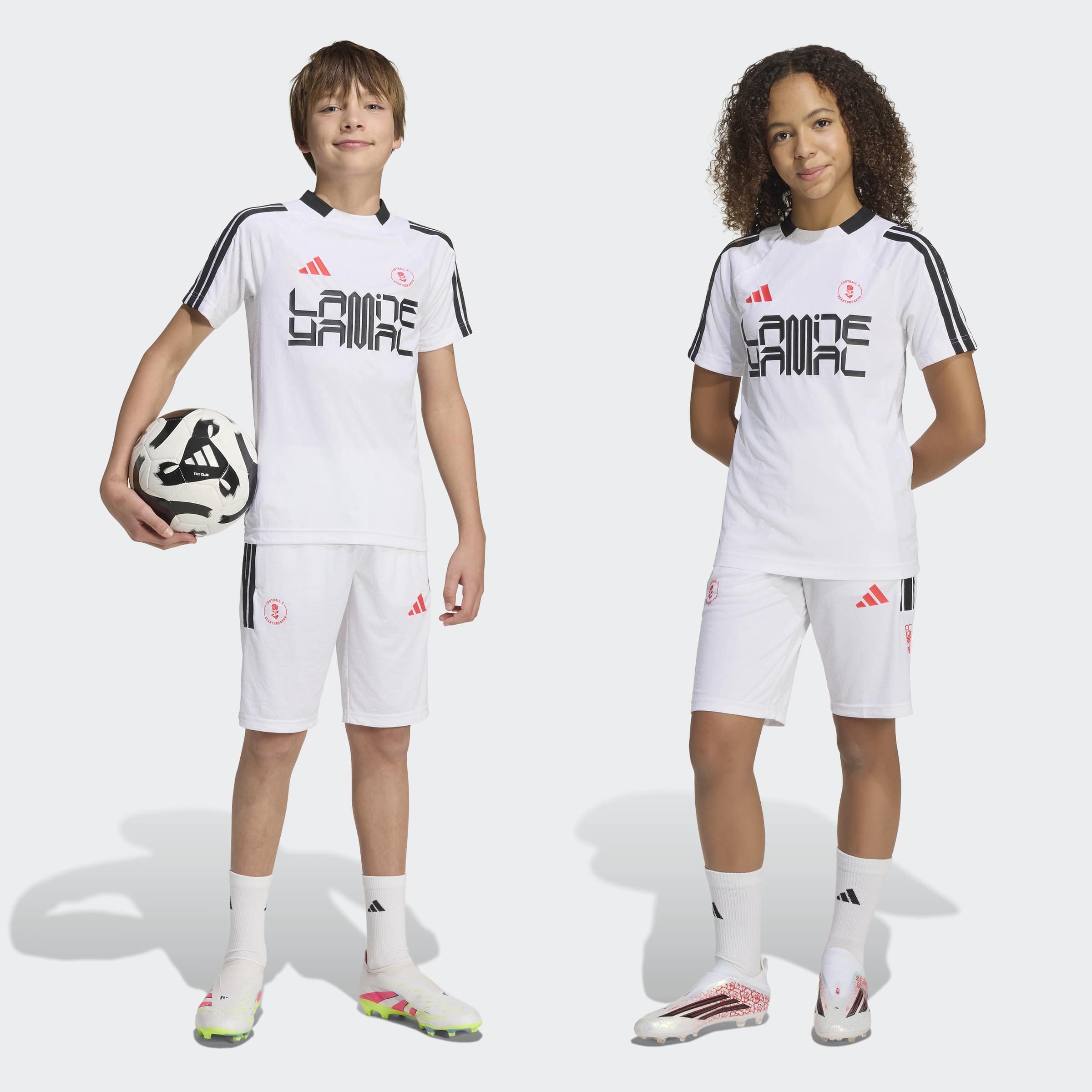 ילדים לבושים במדי כדורגל לבנים עם פסים שחורים, עומדים, כדור ביד