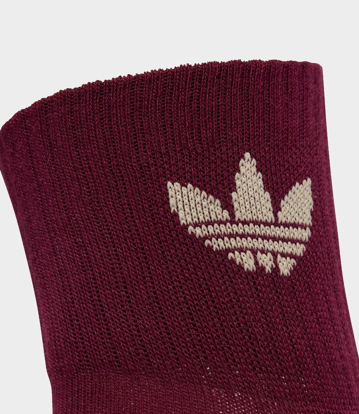 גרב ספורט בורדו עם סמל עלים בהיר ארוג, טקסטורת בד צפופה, צילום תקריב