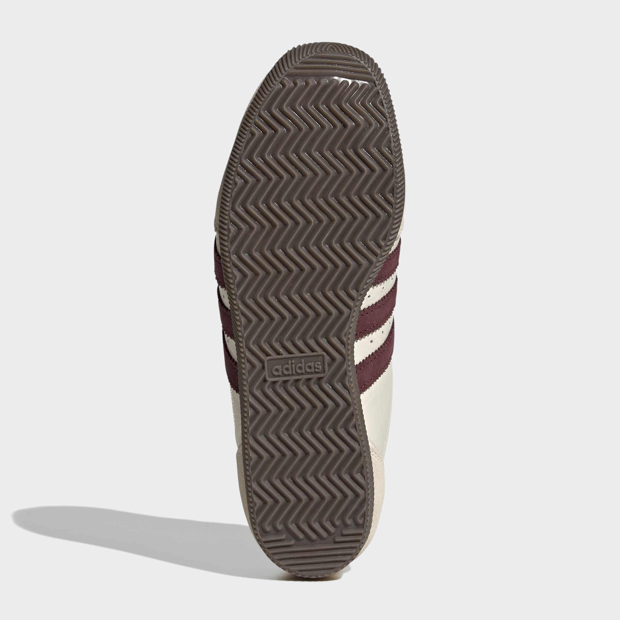 סוליית נעל ספורט גומי חום עם דוגמת זיגזג ומיתוג, פסים אדומים ולבנים בצד