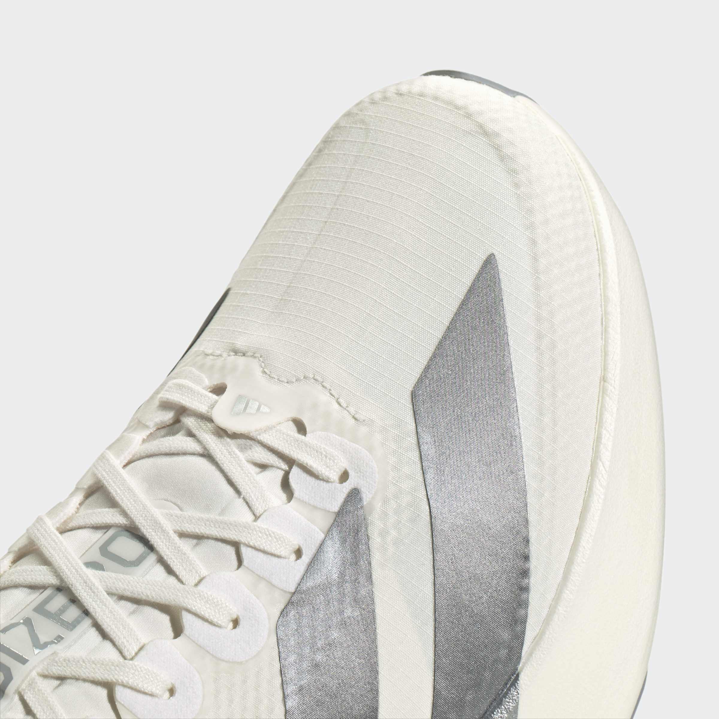 תקריב נעל ספורט אופנתית בצבע לבן עם שרוכים וסמל גרפי כסוף