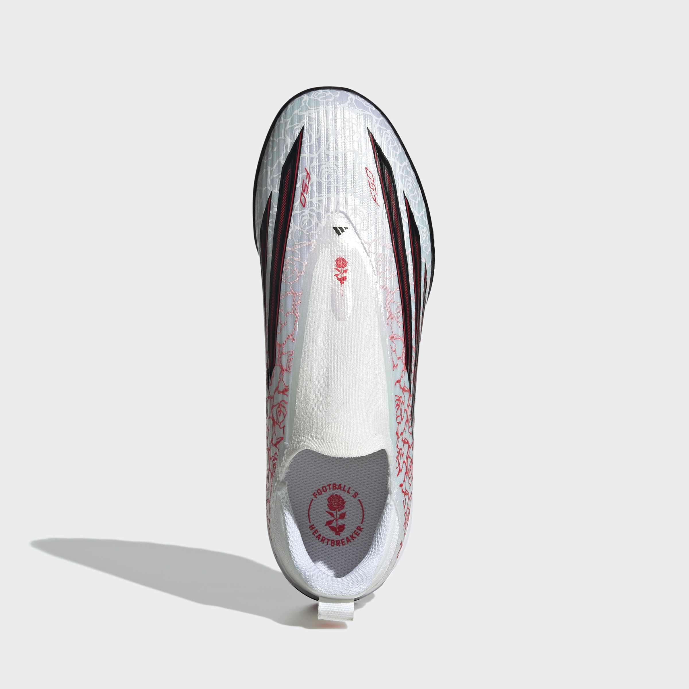 נעל כדורגל לבנה עם פסים שחורים ועיטורי ורדים אדומים, צילום מלמעלה