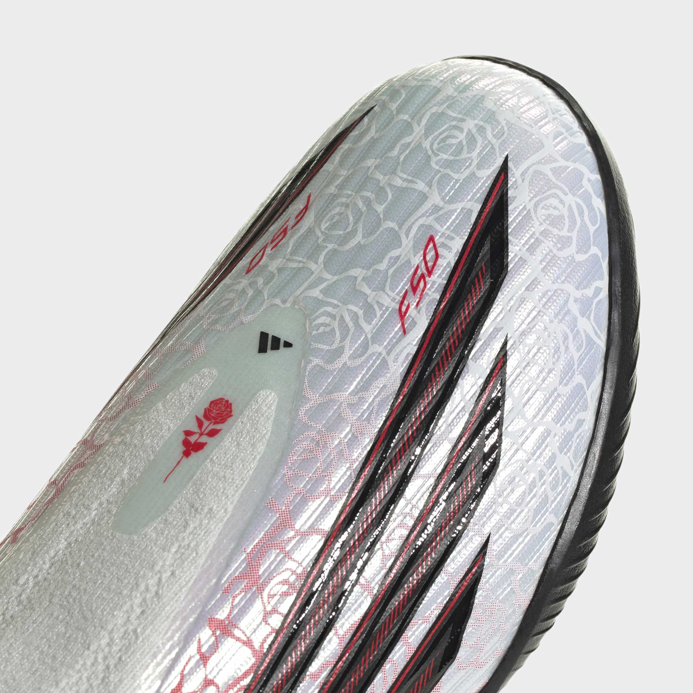 תקריב נעל כדורגל בצבע אפור עם דוגמת ורדים, פסים שחורים ואותיות F50 אדומות