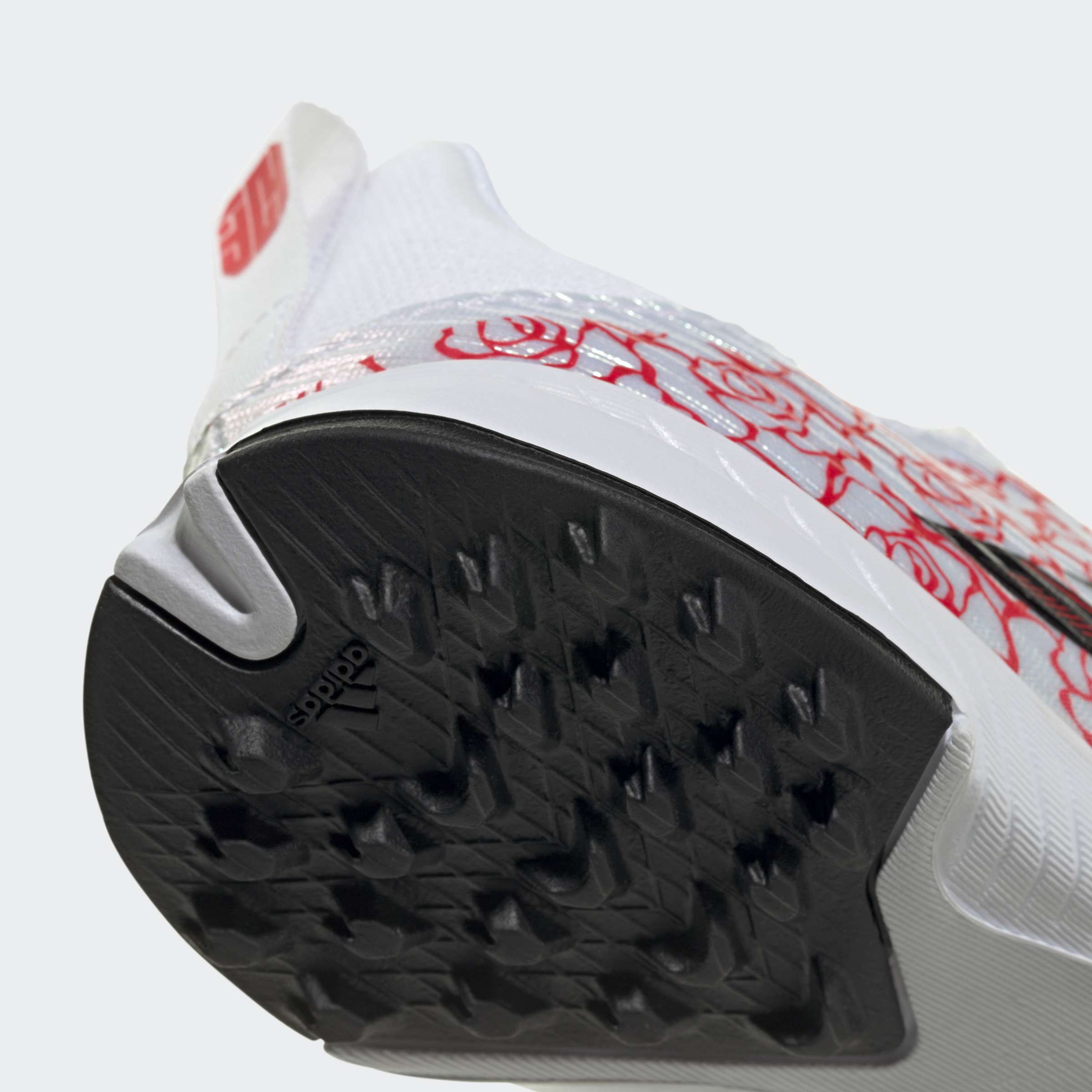 תקריב סוליית נעל ספורט לבנה עם דוגמת אחיזה שחורה ועיטורים אדומים